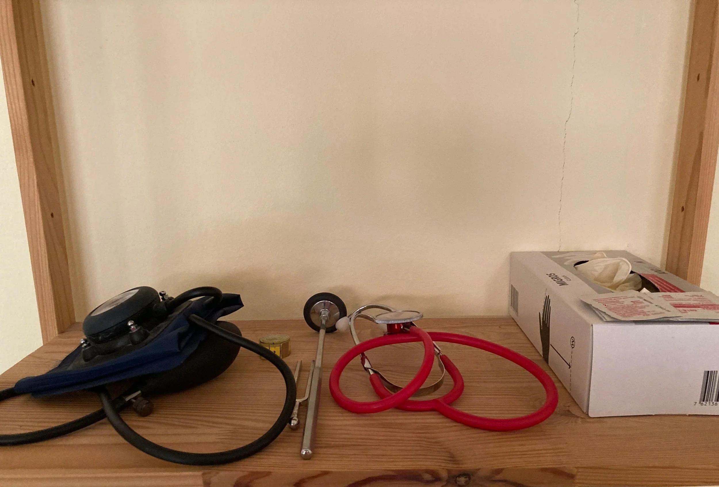 Étagère en bois avec un tensiomètre un ruban à mesurer, un stéthoscope, une boîte de gants.