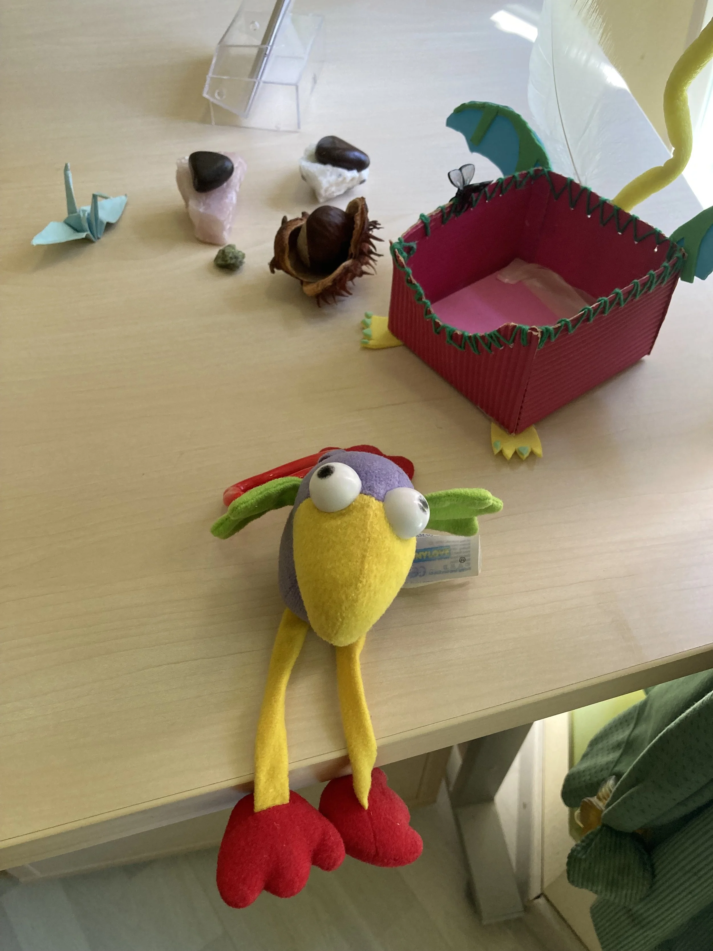 Des marrons et un origami, une boîte à papier et un oiseau en peluche, placée sur une surface en bois.