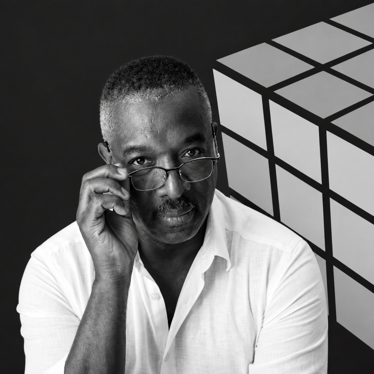 Black and white portrait of a man with short hair and glasses, wearing a white shirt, looking directly at the camera, with a low-poly Rubik's cube graphic in the background.