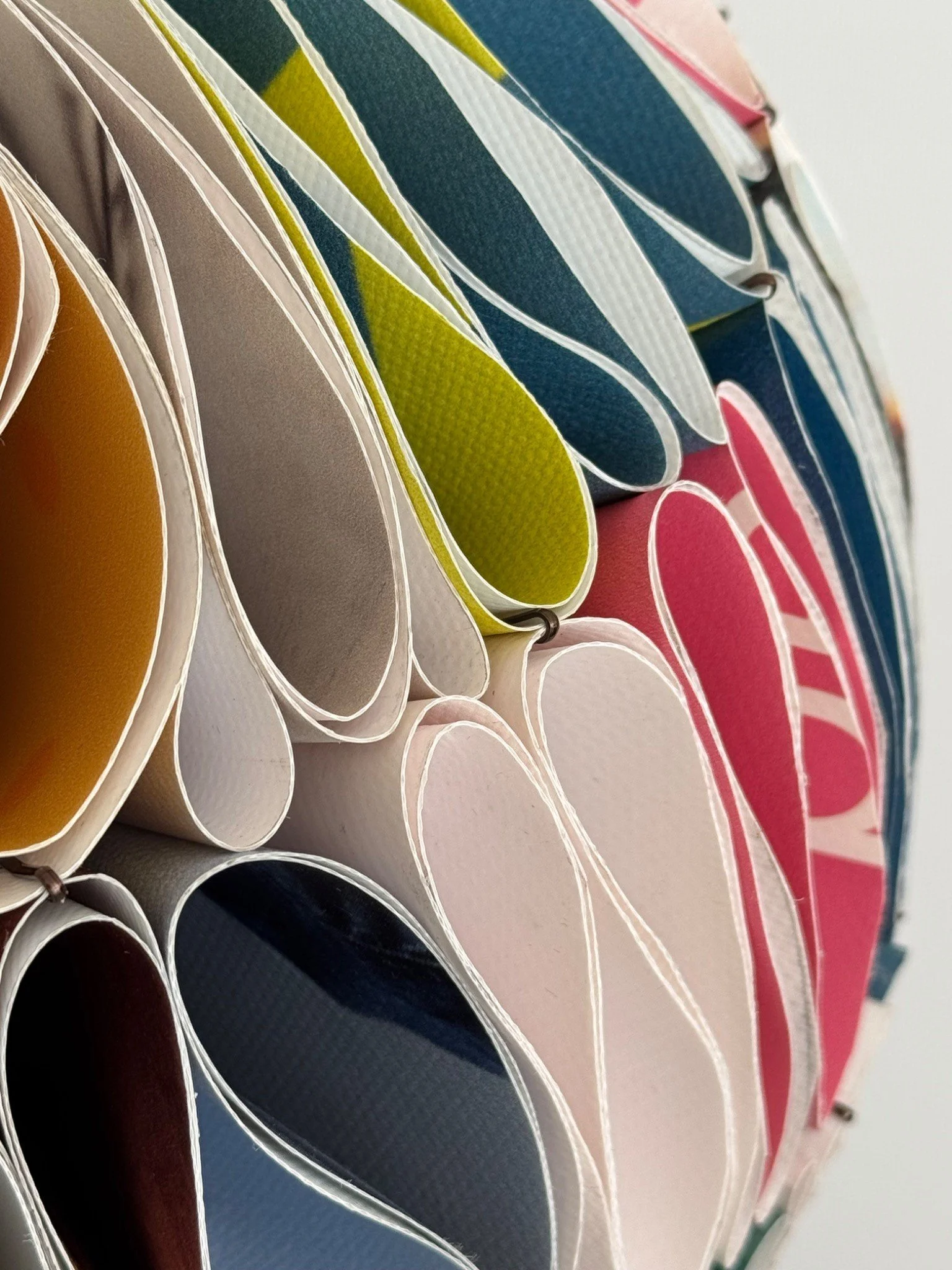 Close-up of colourful reclaimed advertising banners folded into the layered structure of a NJITS lampshade.