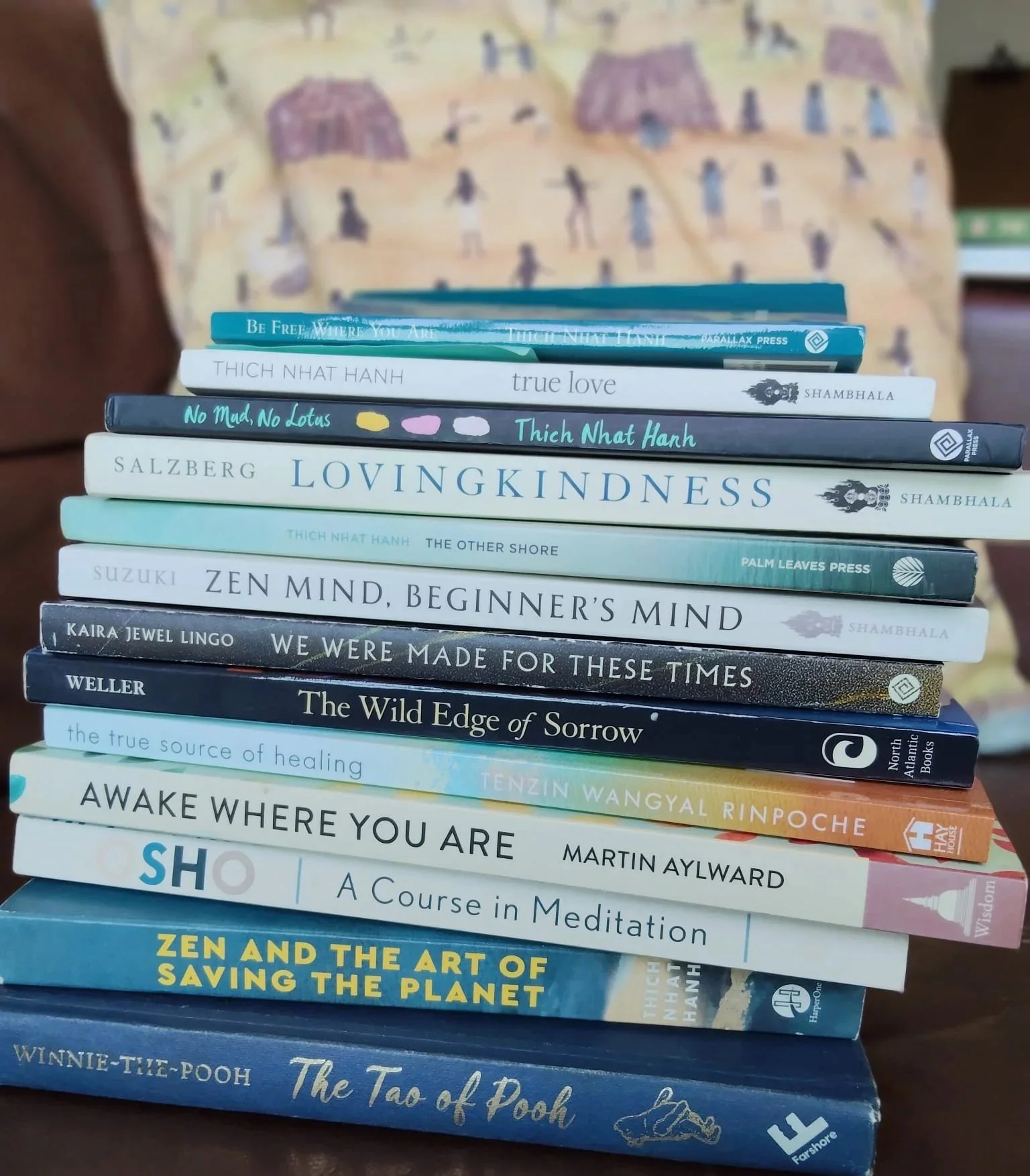 Pile of books on meditation, love, kindness, art, and environmental topics, with various titles and authors visible.