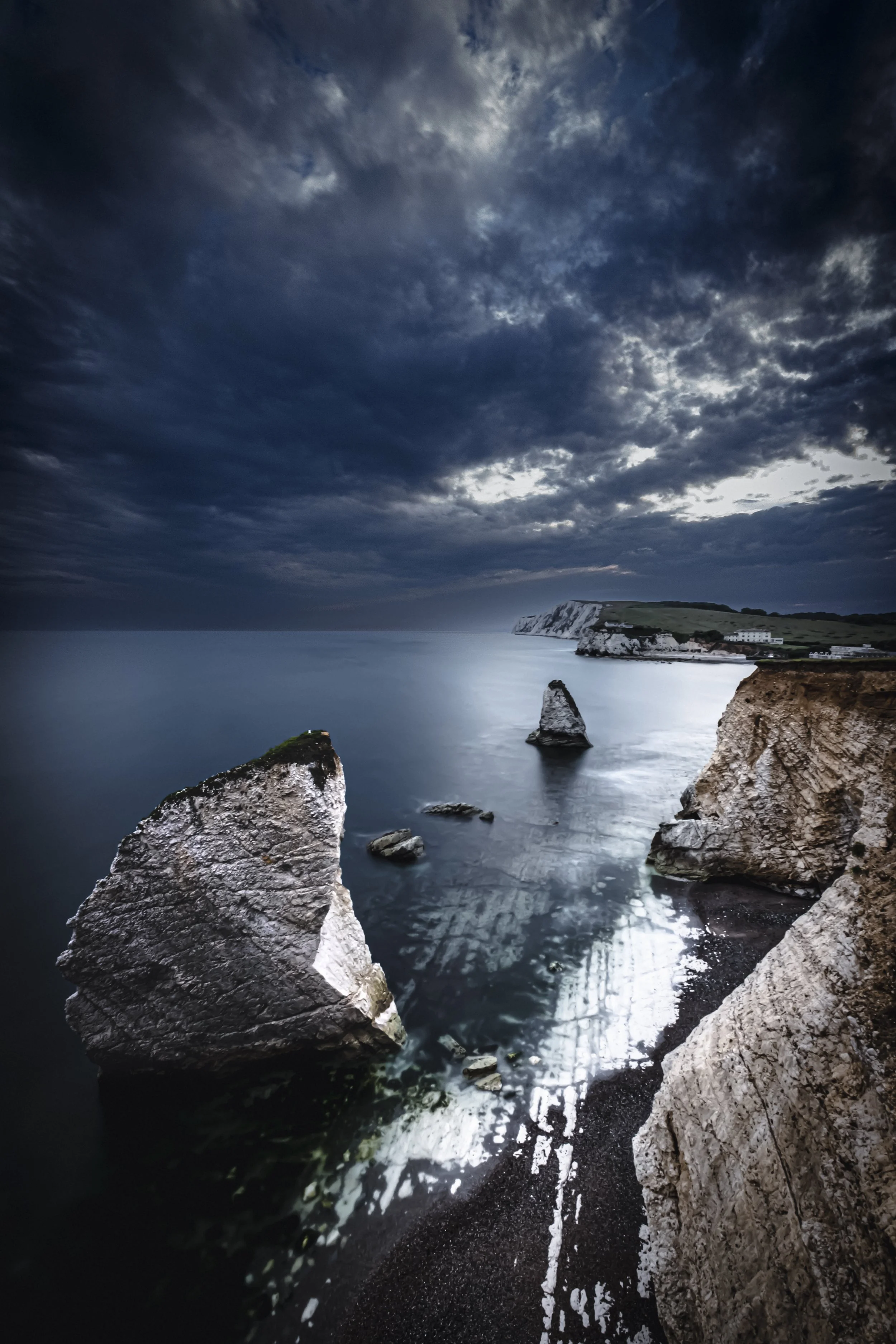 Cliffs over the ocean during dusk with dark, cloudy sky.