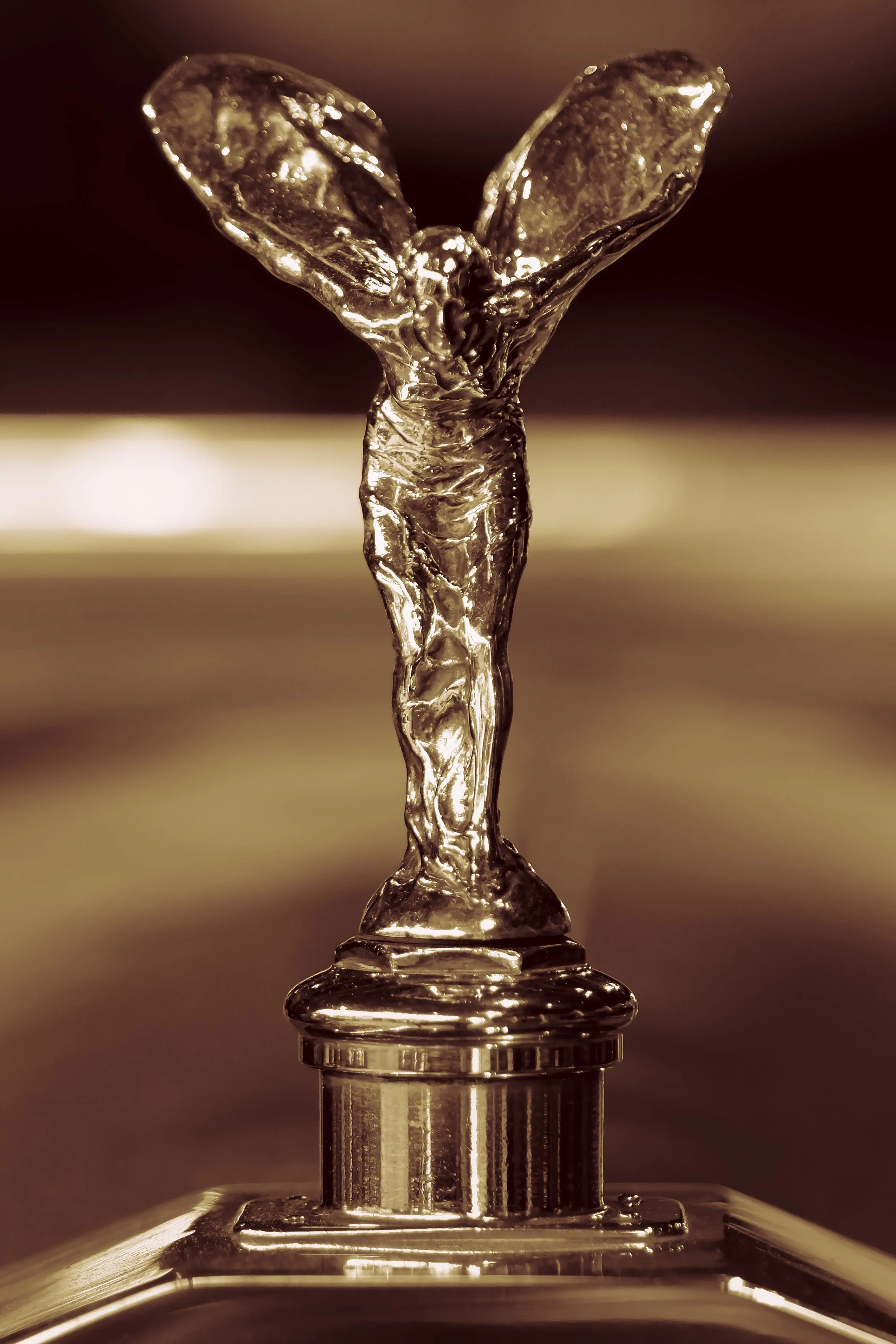 Close-up of a metallic trophy or award in the shape of a person with wings, standing on a circular base.