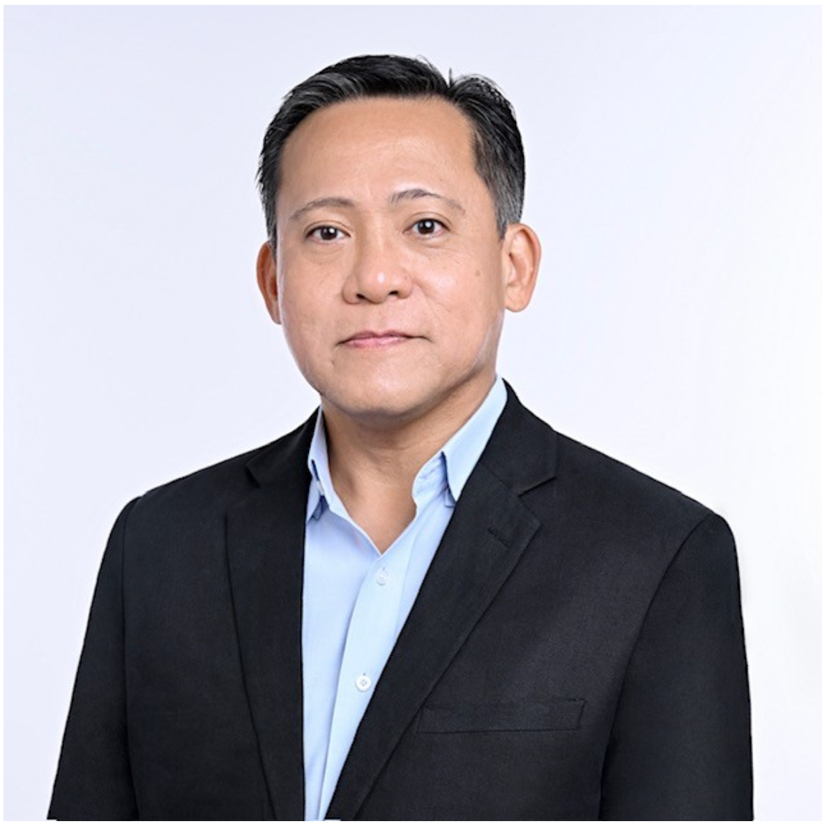 A professional man in a black suit and light blue dress shirt, posing against a plain white background.