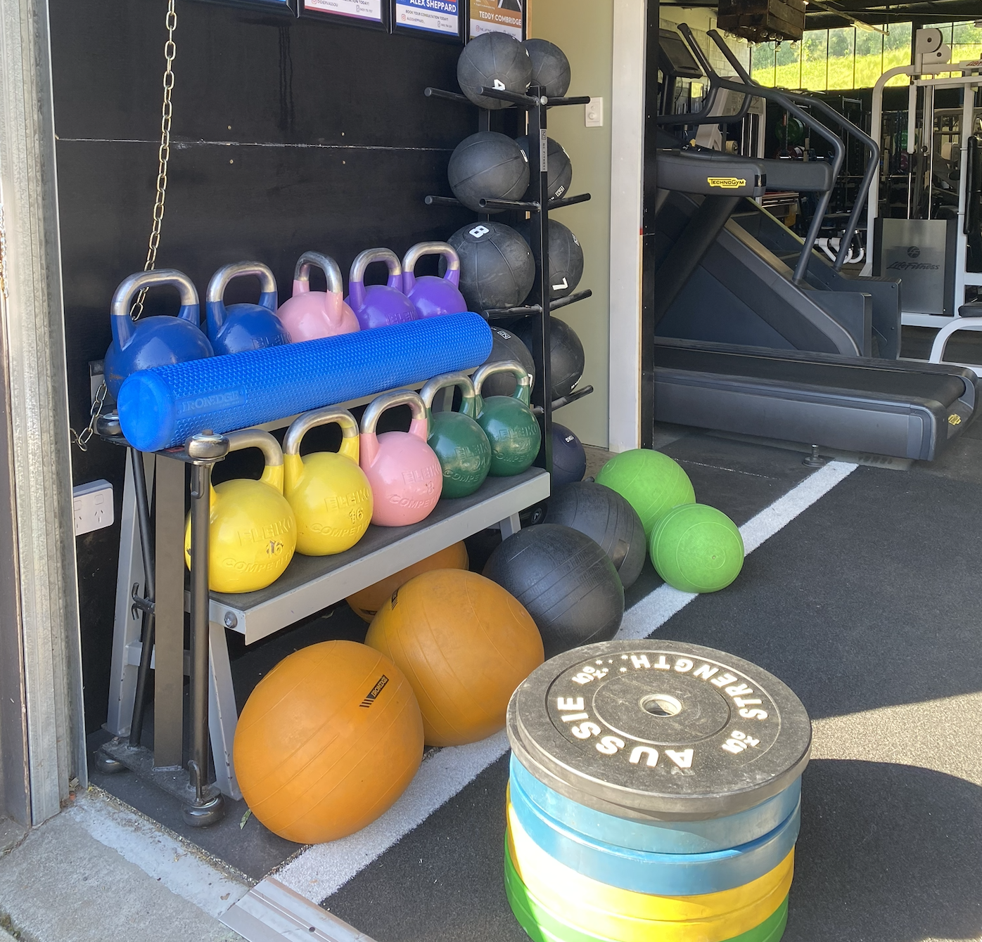 A variety of colorful kettlebells, medicine balls, and exercise equipment in a gym or fitness center.