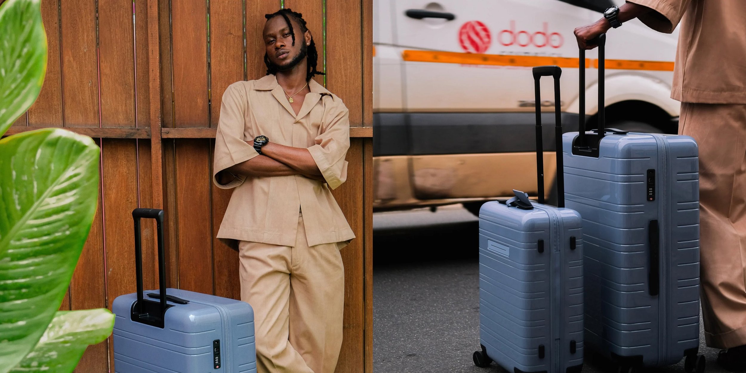 A man in beige clothing leaning against a wooden wall with two blue suitcases nearby, and a person with brown clothing holding their suitcase on an urban street.