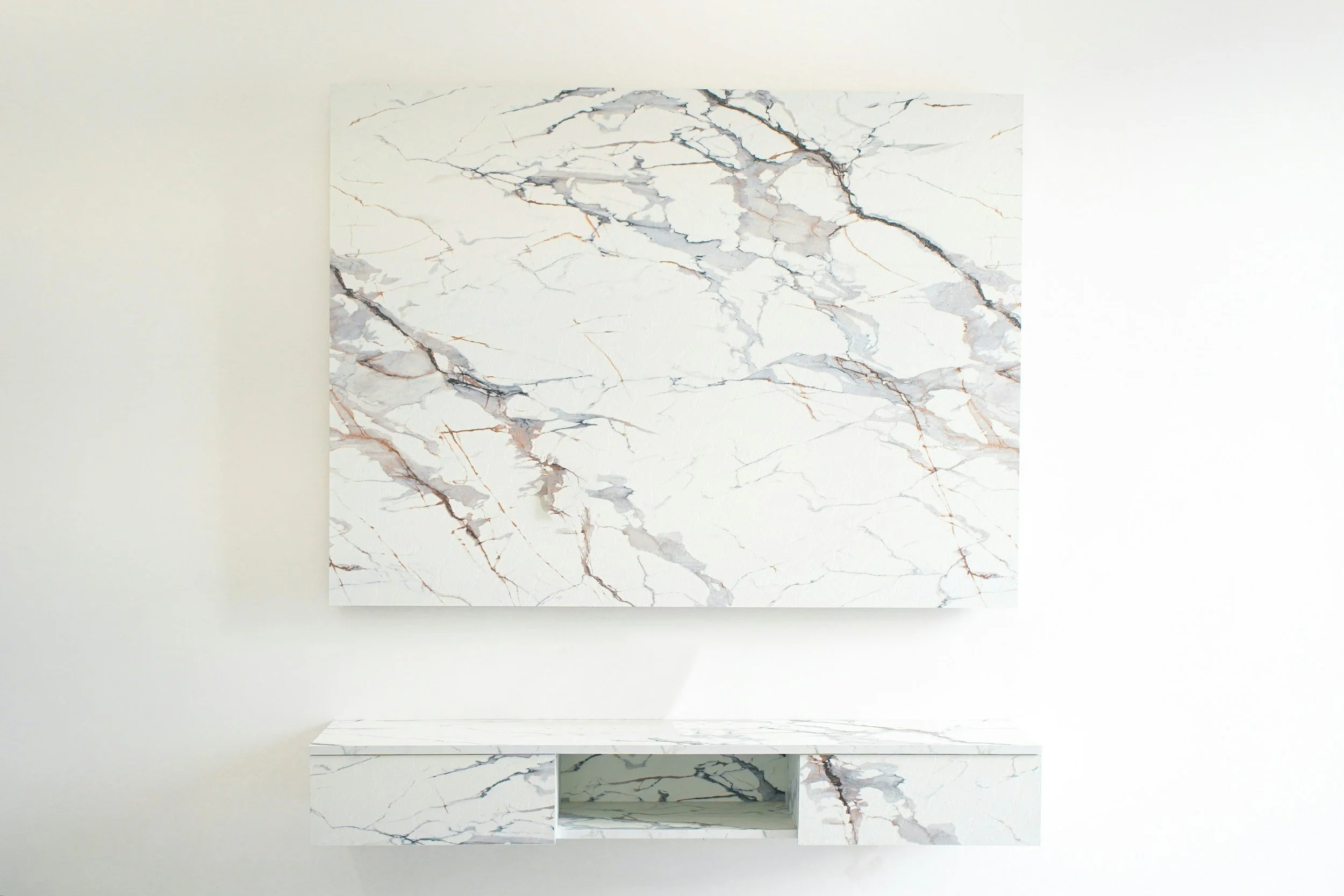 A marble wall with a marble shelf beneath it, both featuring a white base with gray and gold veining.