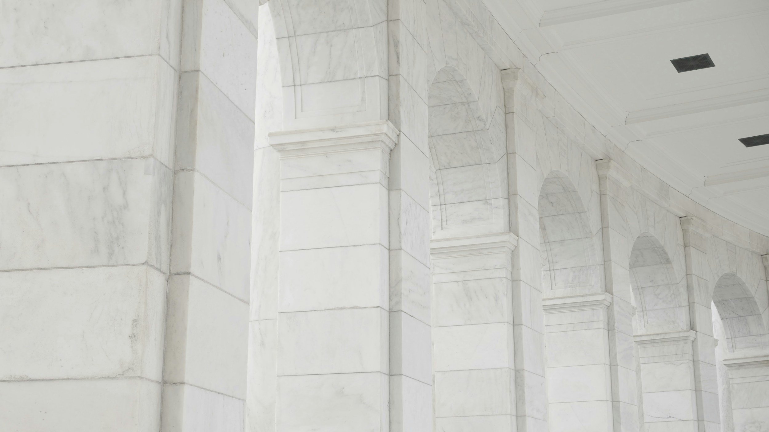 Close-up of a marble architectural wall with arches and columns.