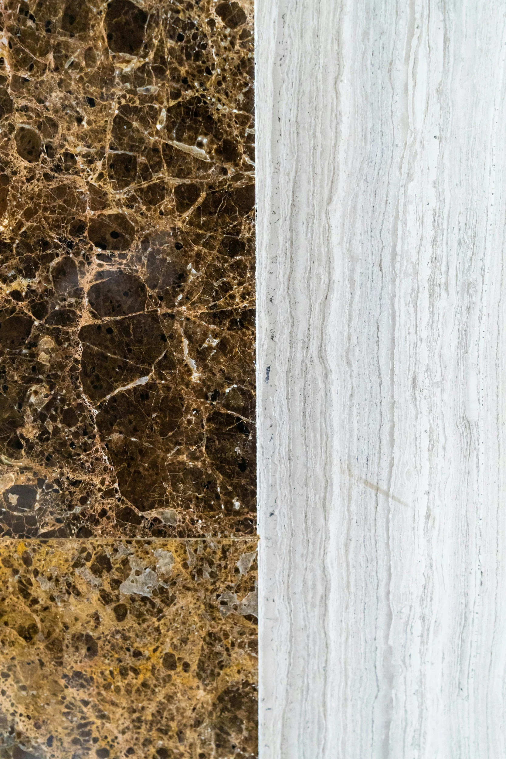 Two different types of marble countertops, one dark brown with tan, black, and white speckles, and the other light gray with subtle veining.