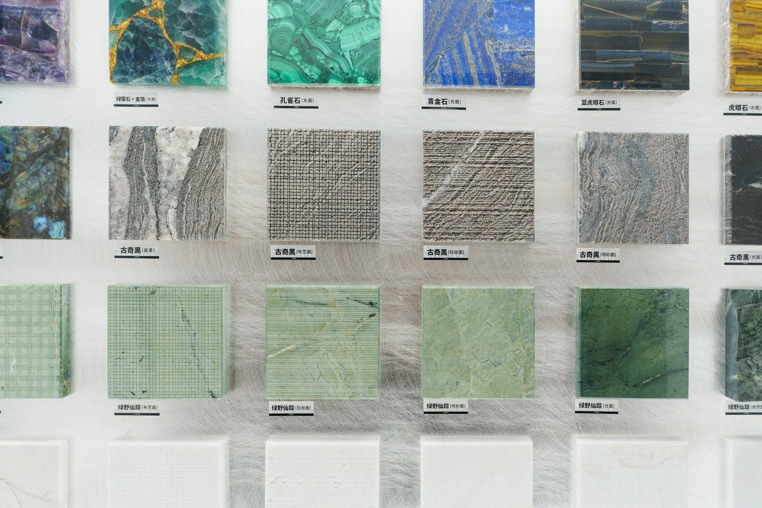 A display of various marble and stone tiles with different colors and patterns, labeled with Chinese characters.