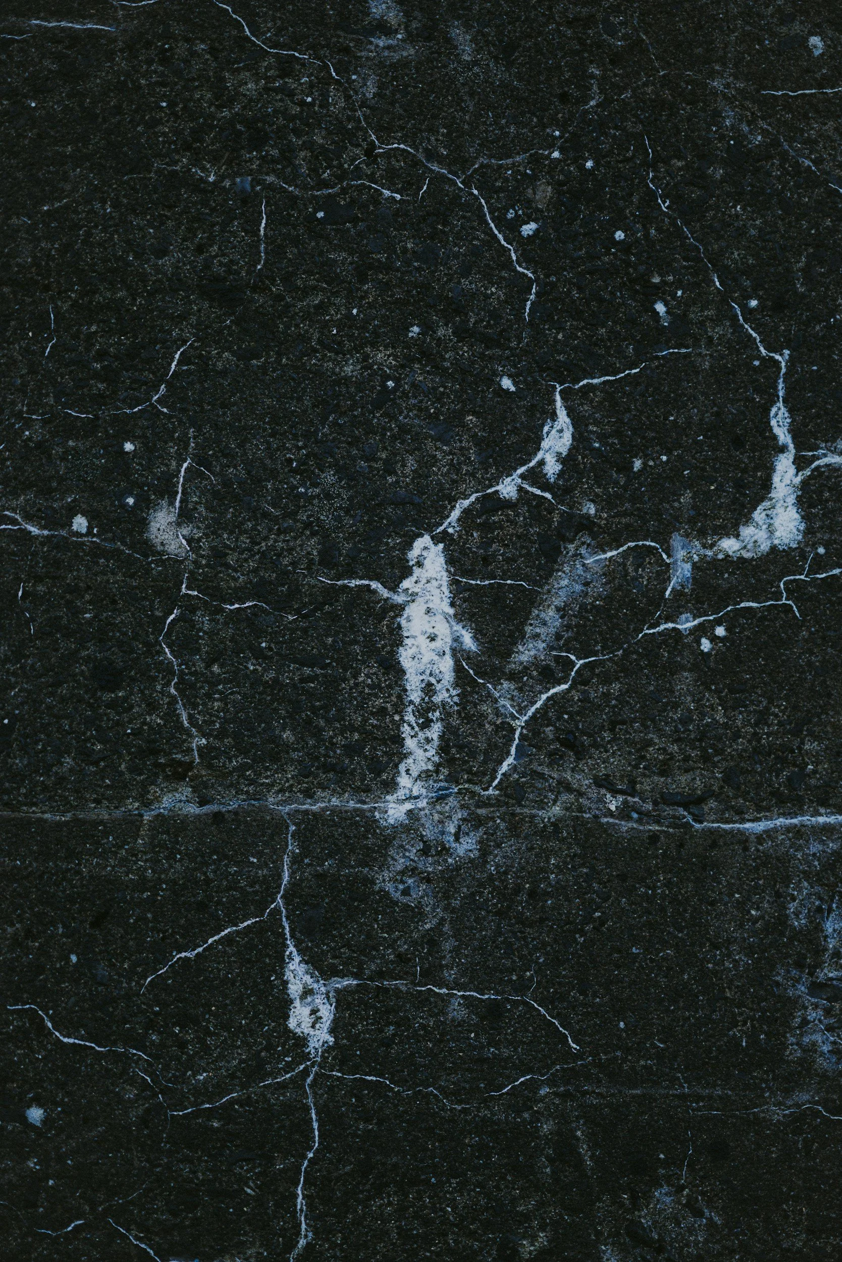 Close-up of black marble surface with white veins and cracks.