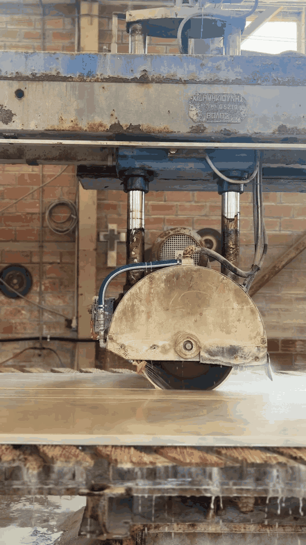 Close-up of an industrial circular saw cutting through a piece of wood in a workshop.
