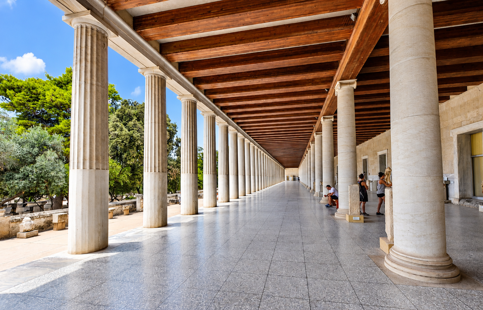 Columned walkway with marble columns, a wooden ceiling, and people viewing sculptures.
