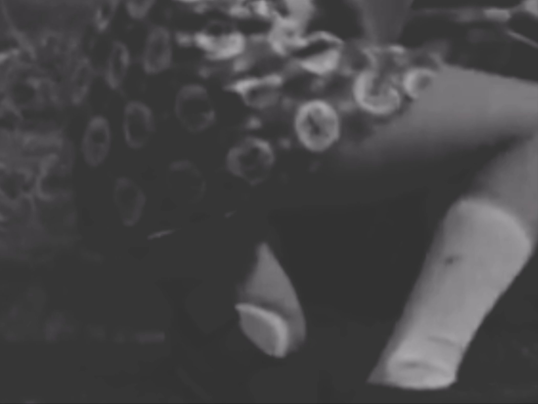 A blurry black and white photo of a pile of glass jars or bottles on a wet surface.
