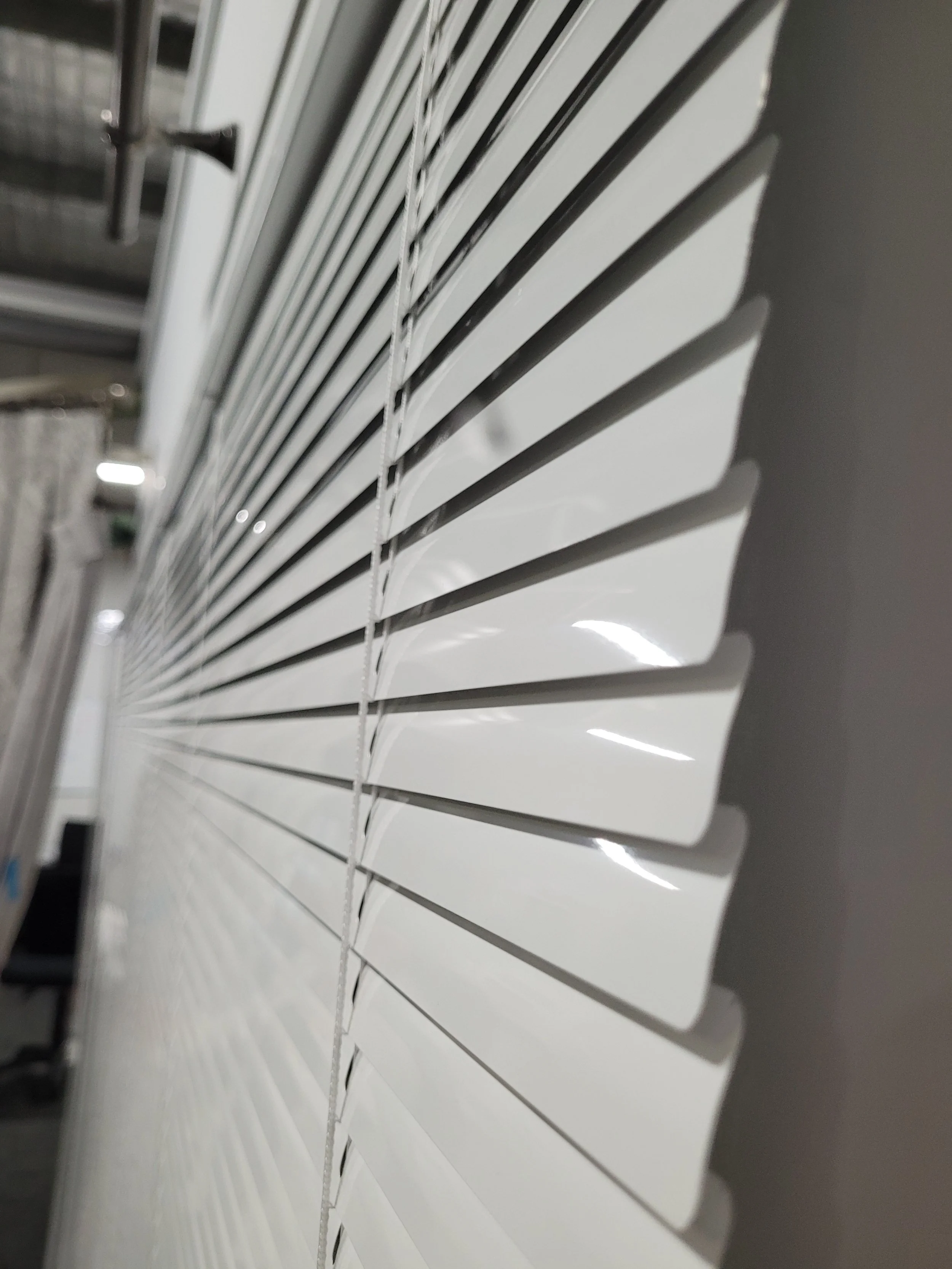 Close-up of white horizontal window blinds with a black window latch in the background.