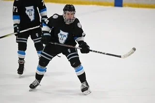 Ice hockey player in black jersey with number 94, skating on ice with hockey stick