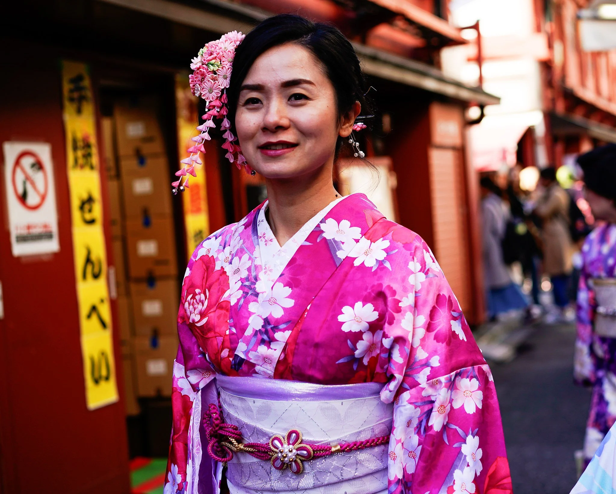 Woman in a pink kimono smiling on an Asakusa shopping street
