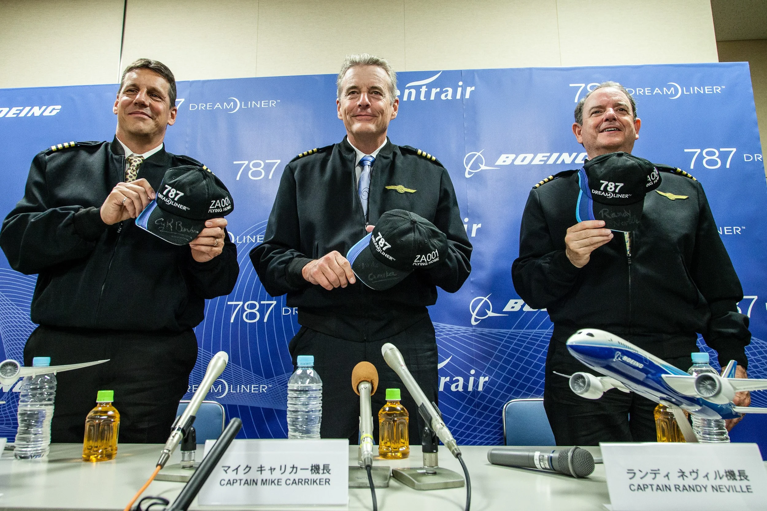 Captains Mike Carriker and Randy Neville at a Boeing 787 Dreamliner press conference, holding signed caps