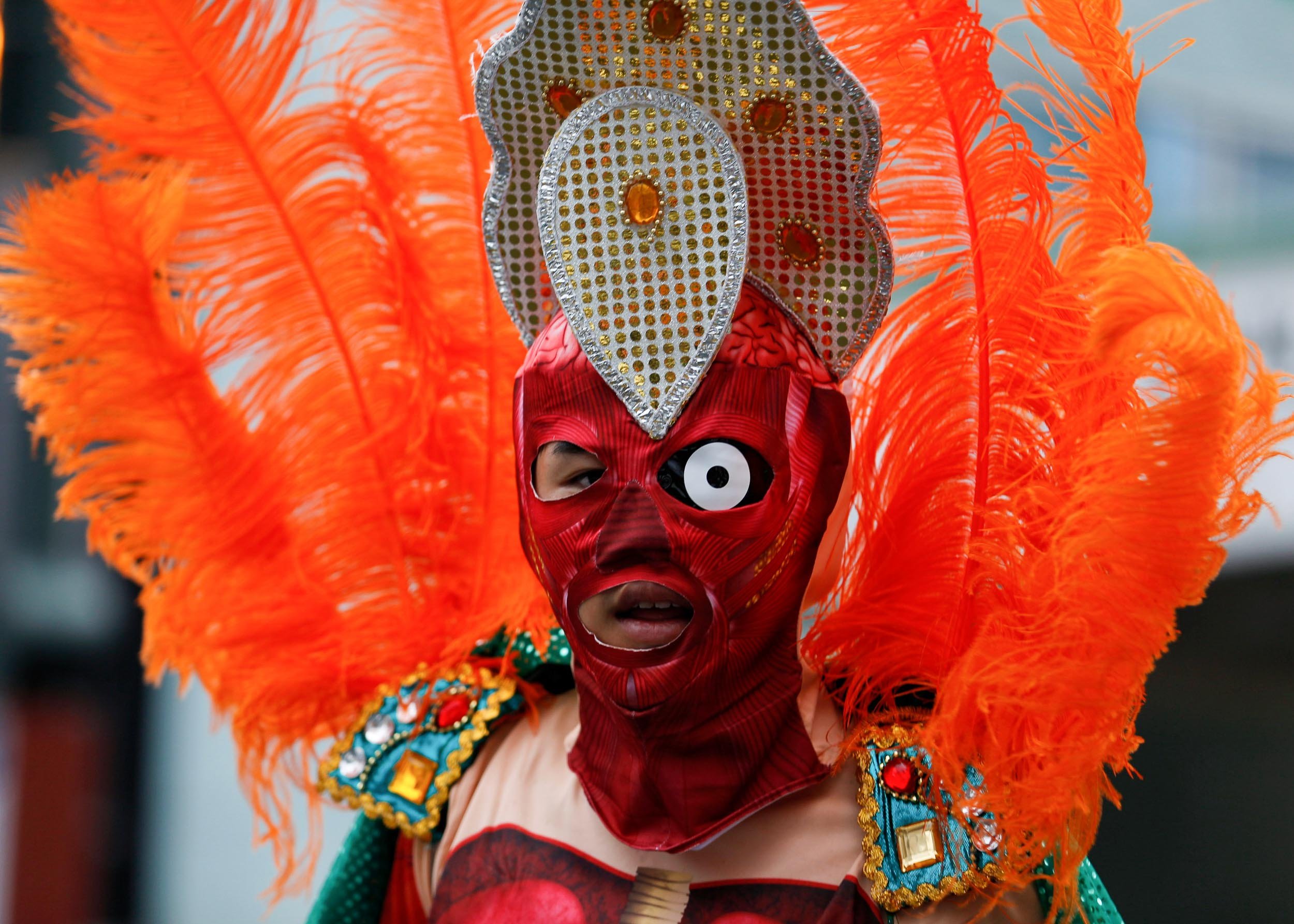Costumed performer in a red mask and orange feather headdress at the Asakusa Samba Carnival, Tokyo.