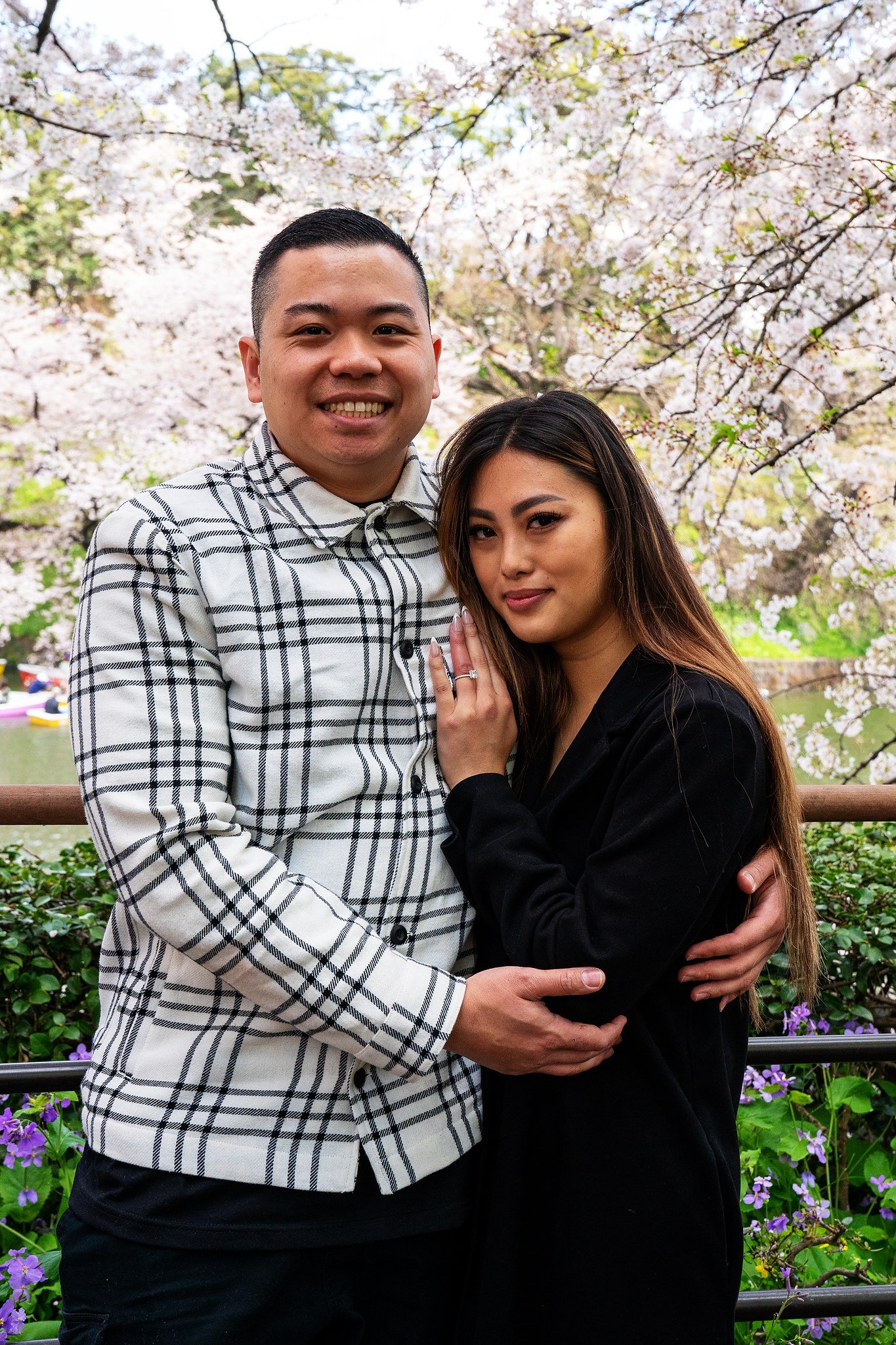 Newly engaged couple embracing under cherry blossoms in Tokyo