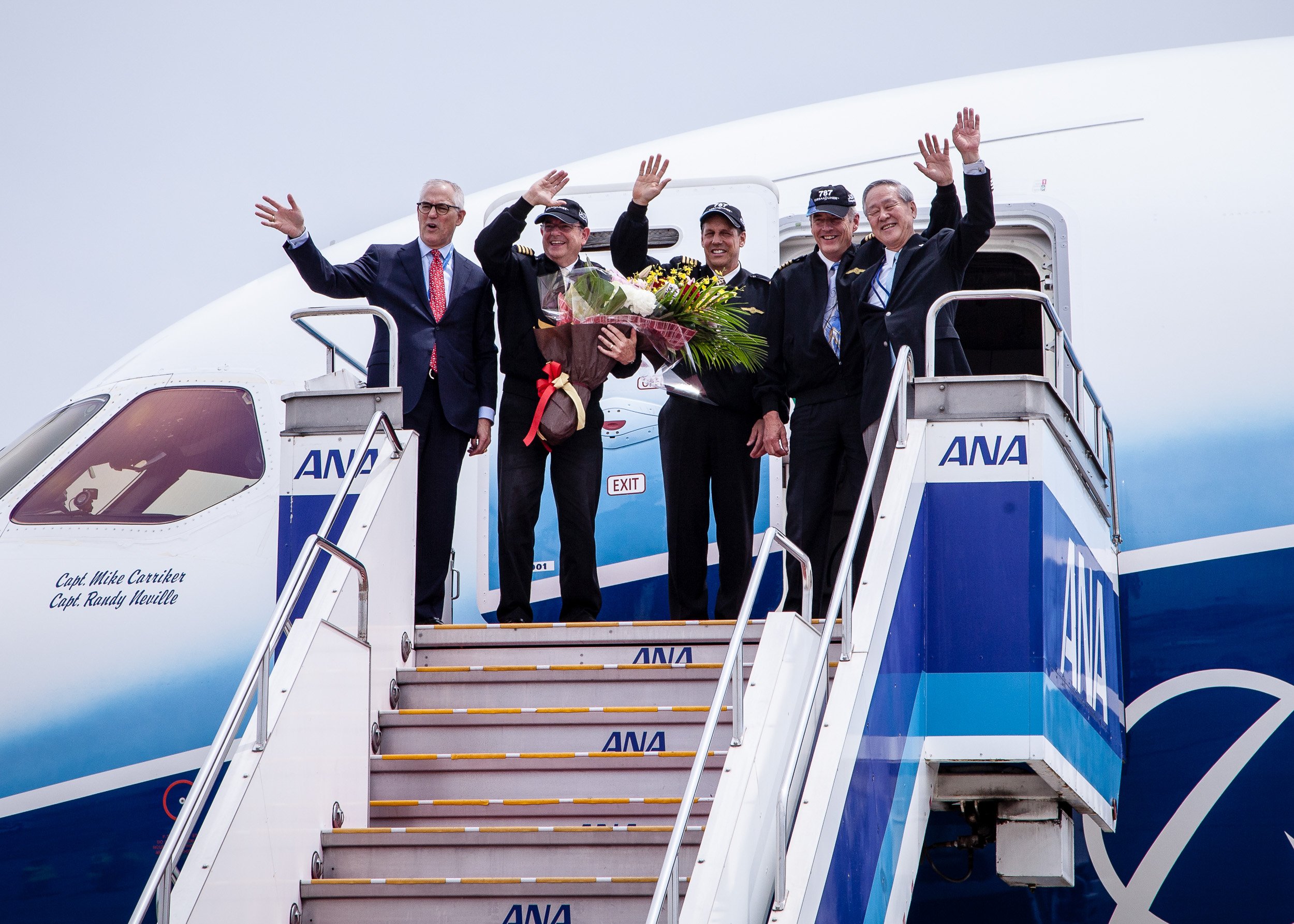 Boeing 787 Dreamliner crew waving with flower bouquets during a celebratory arrival