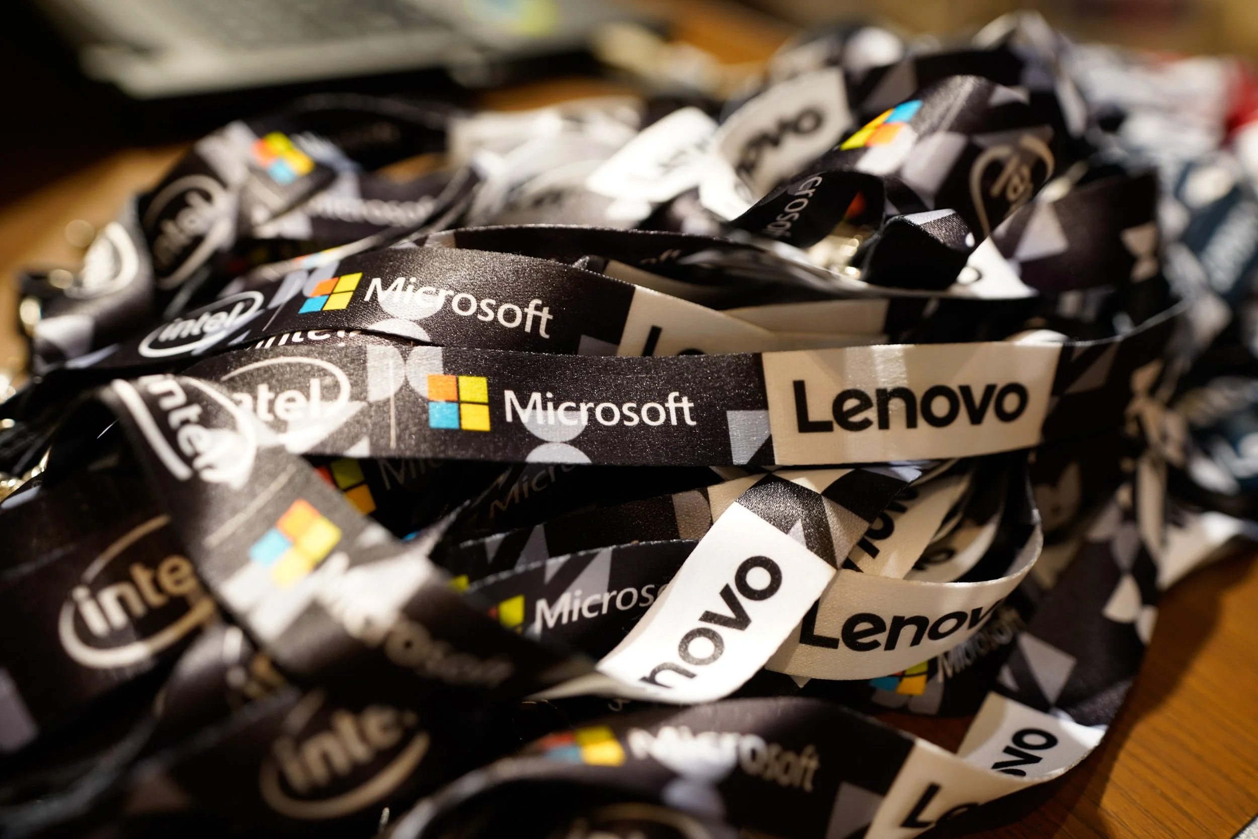 Close-up of sponsor lanyards from Microsoft, Lenovo, and Intel at a conference