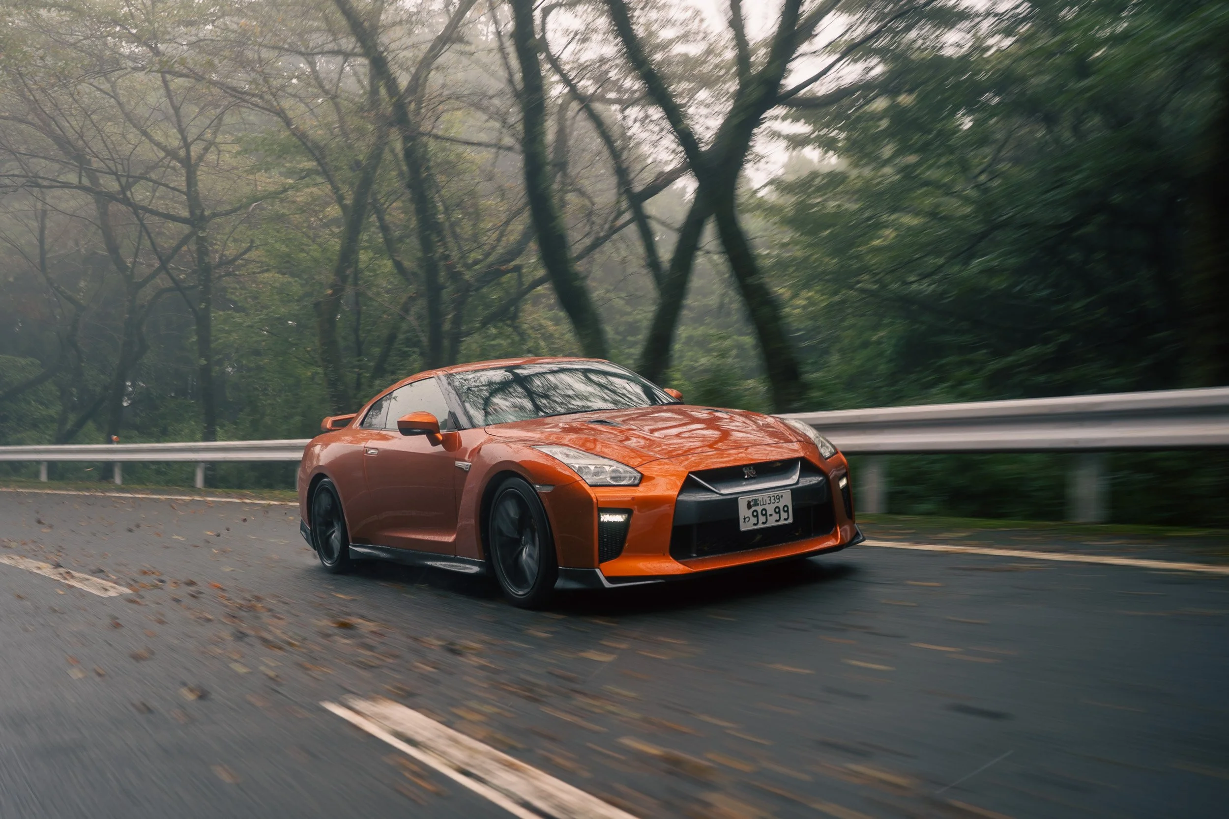 Orange Nissan R35 GT-R rolling shot on a misty mountain road at Hakone Turnpike in Japan.
