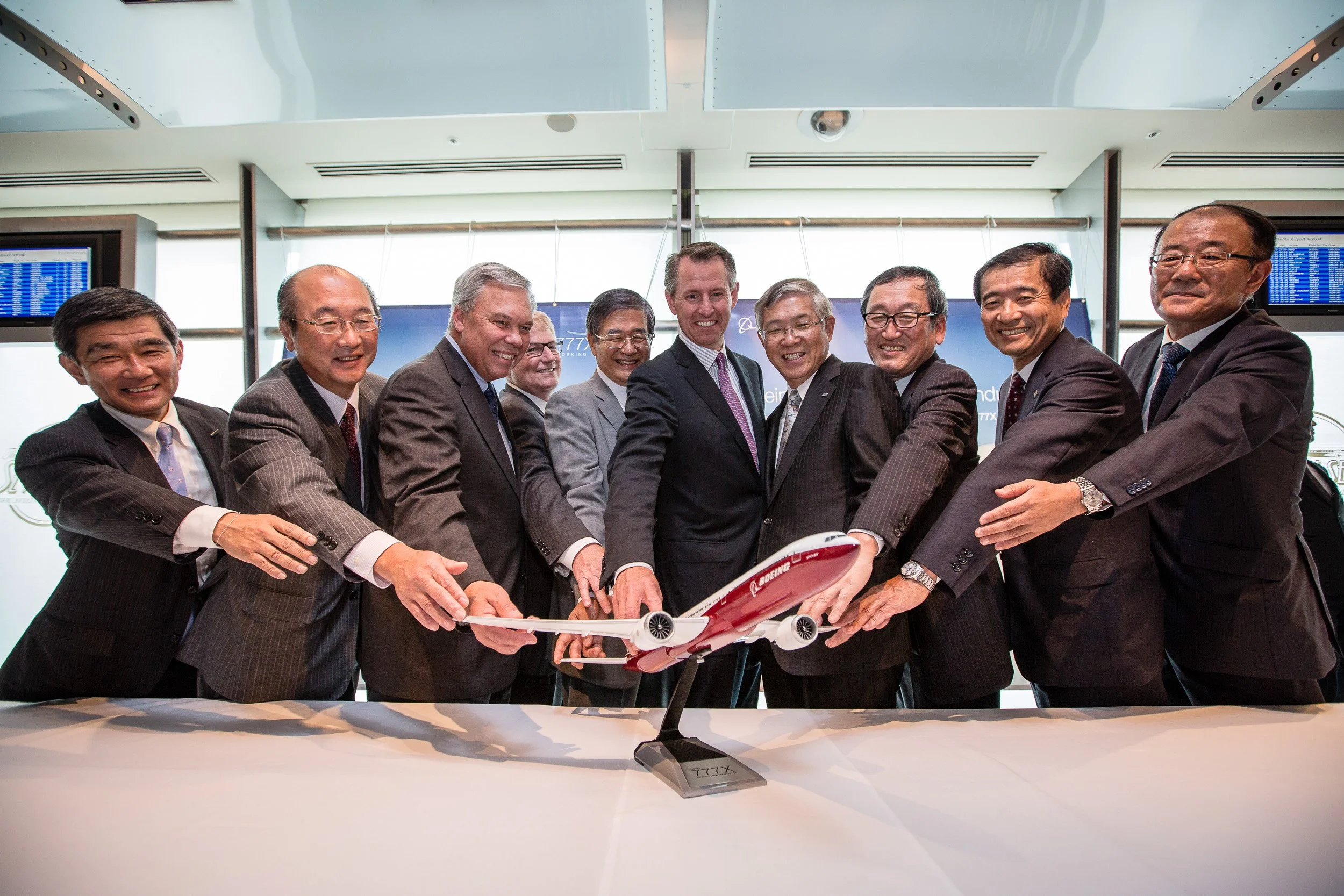 Group of executives holding a Boeing 777X model airplane together