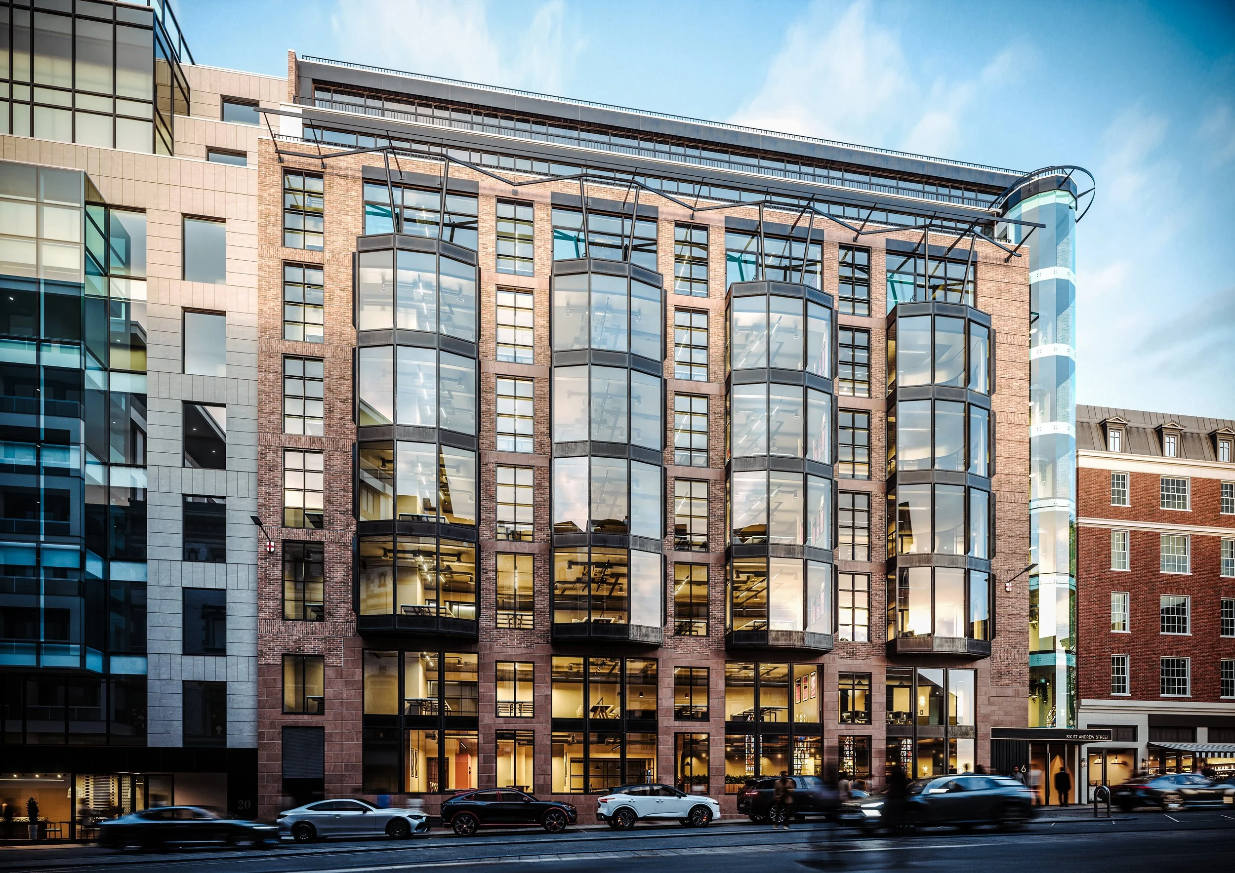Modern multi-story office building with large glass windows, brick accents, and a rooftop terrace, with cars parked along the street in front, under a blue sky with some clouds.