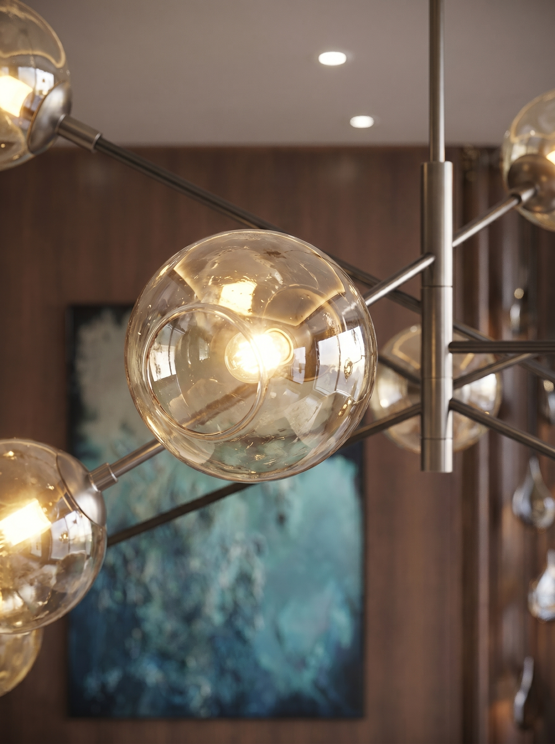 Close-up of modern chandelier with glass globe bulbs in a room with brown walls and ceiling lights.