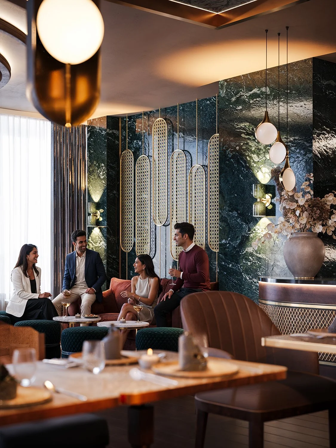 Four people socializing in a modern, upscale lounge or restaurant with elegant decor, gold accents, marble walls, and warm lighting.