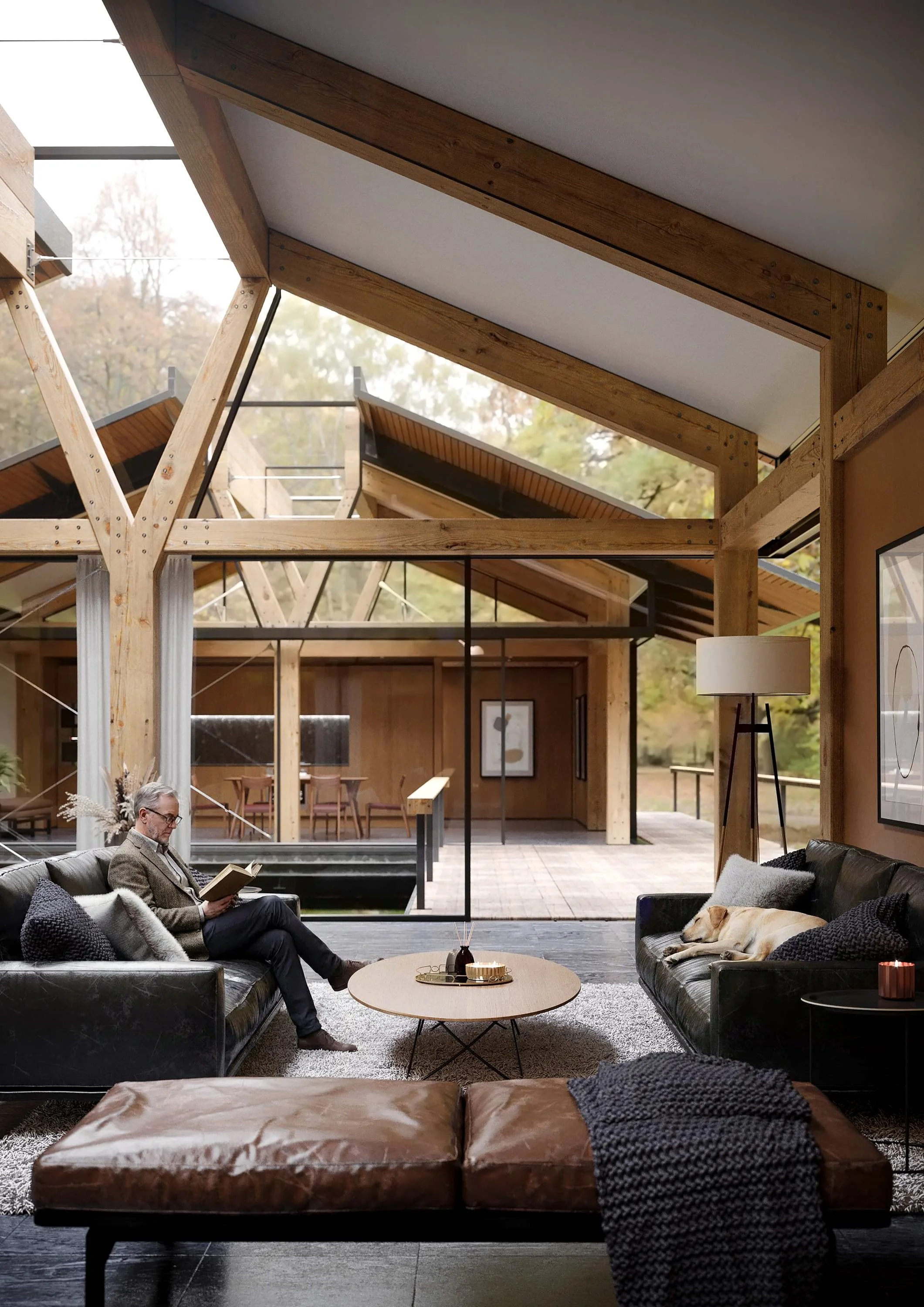 A living room with two black leather sofas and a tan leather ottoman. A man is sitting on one sofa reading a book, and a dog is lying on the other sofa. Large windows show a view of trees outside. The room has wooden beams on the ceiling, modern lamp