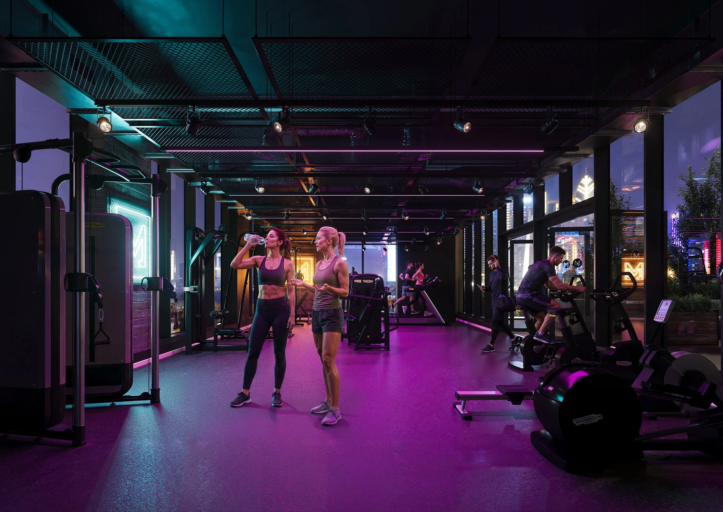 Two women in workout clothes talking and drinking water inside a modern gym with cardio machines and weights at night. Neon lights and city skyline visible through windows.