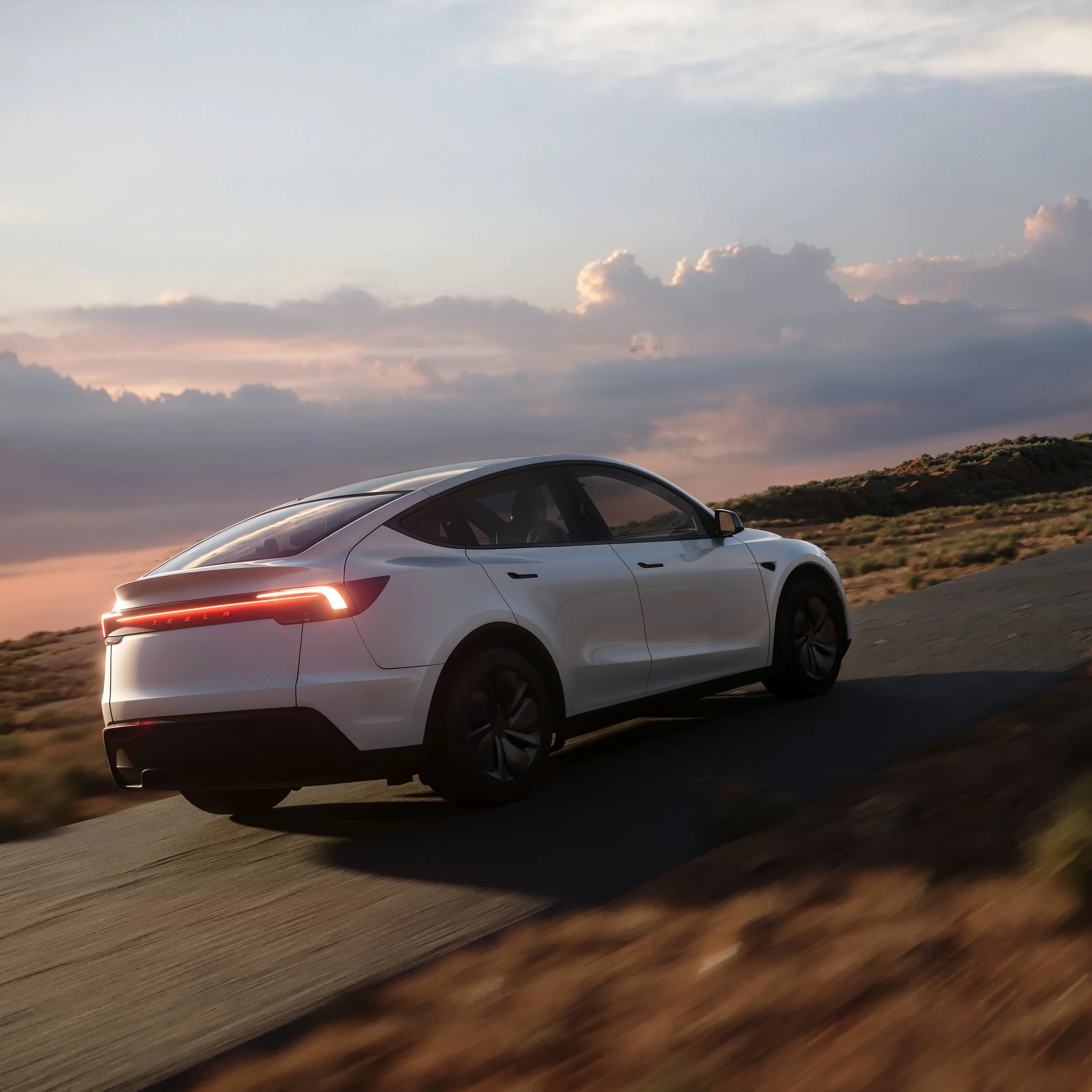 A white Tesla electric vehicle driving on a road during sunset with a partly cloudy sky and landscape in the background.