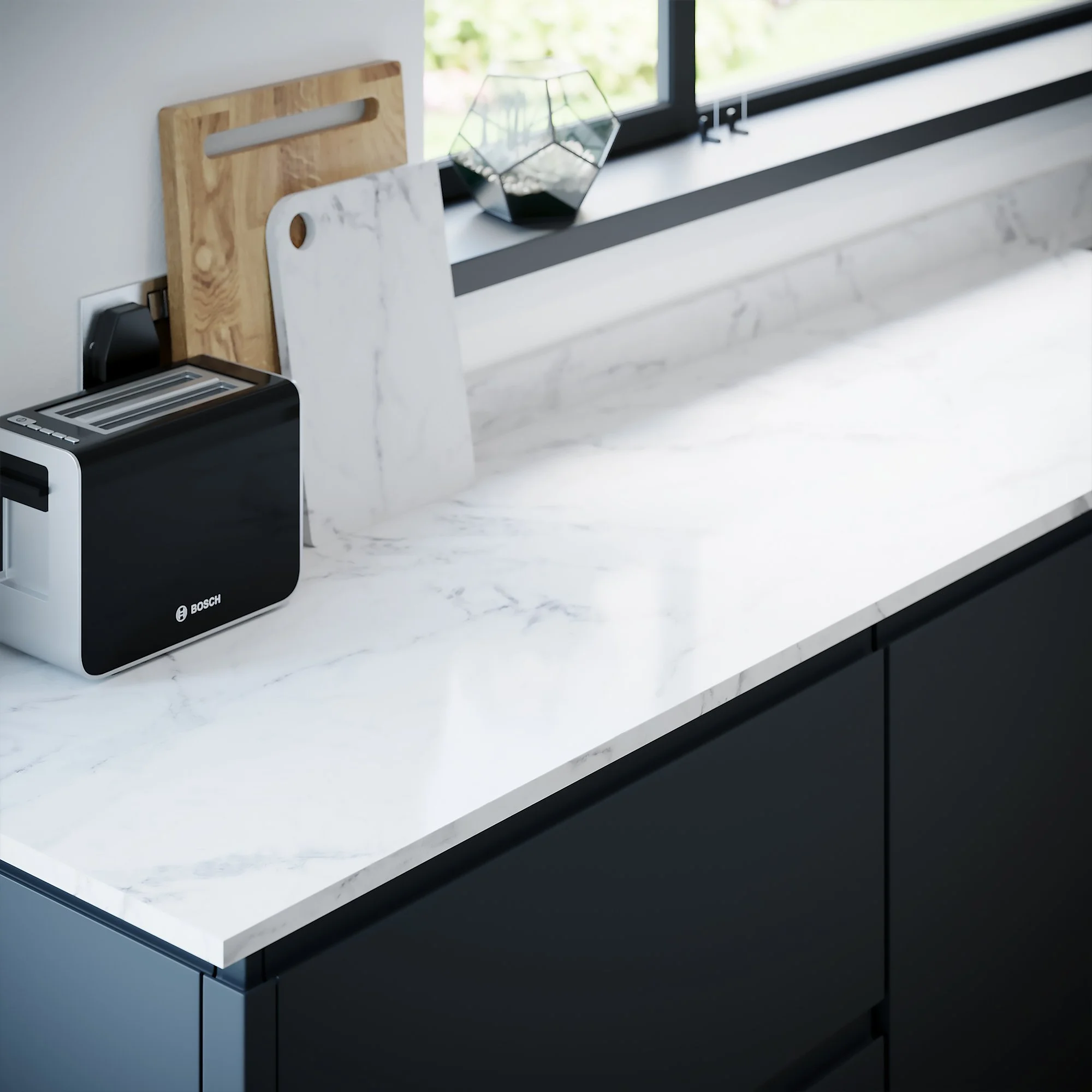 Modern kitchen with dark lower cabinets, white marble countertop, a wooden cutting board, a white paper towel roll, and a Geometric glass terrarium on the window sill.