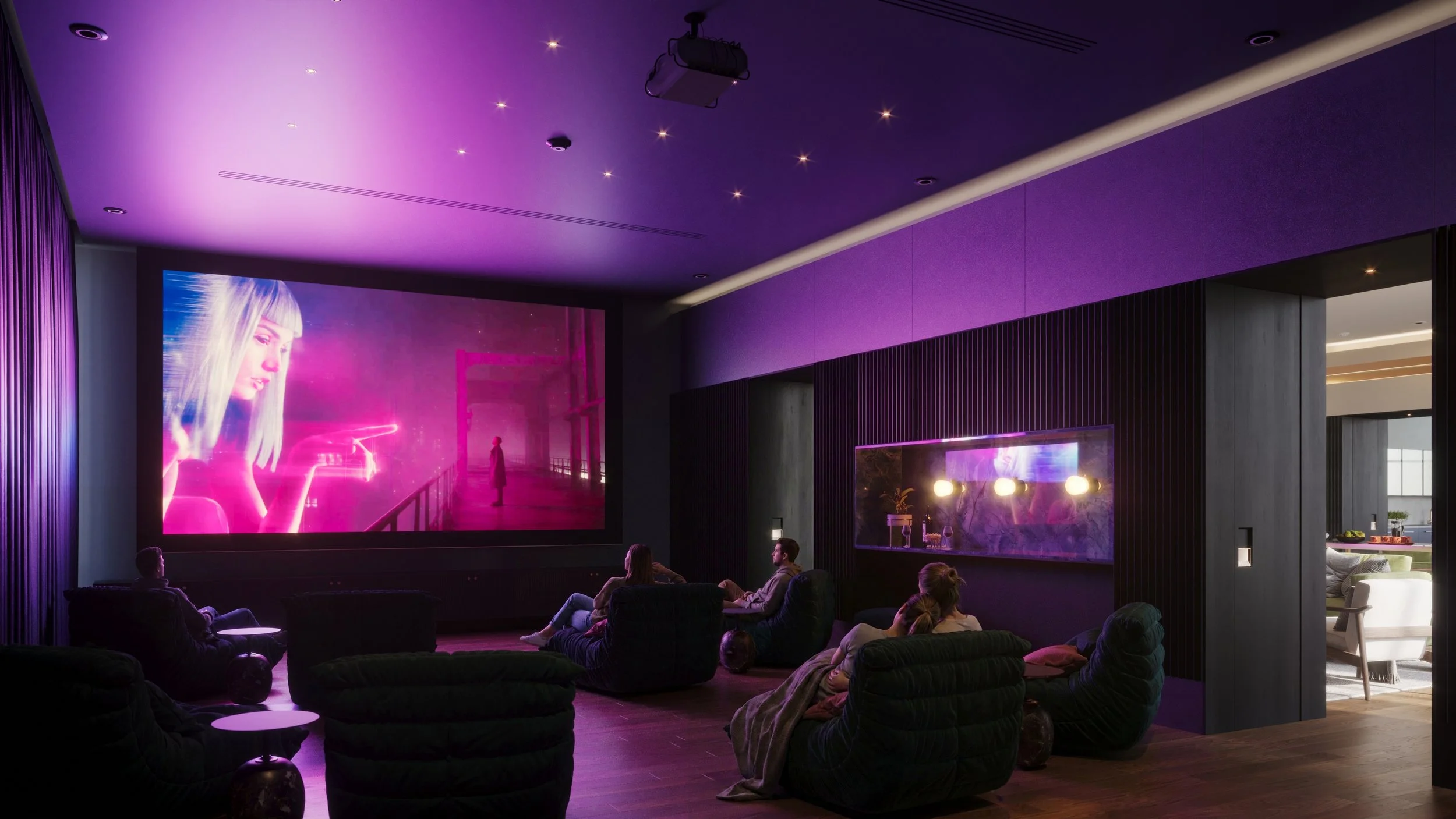 People sitting on black cushioned chairs watching a large screen in a modern home theater with purple and pink lighting.
