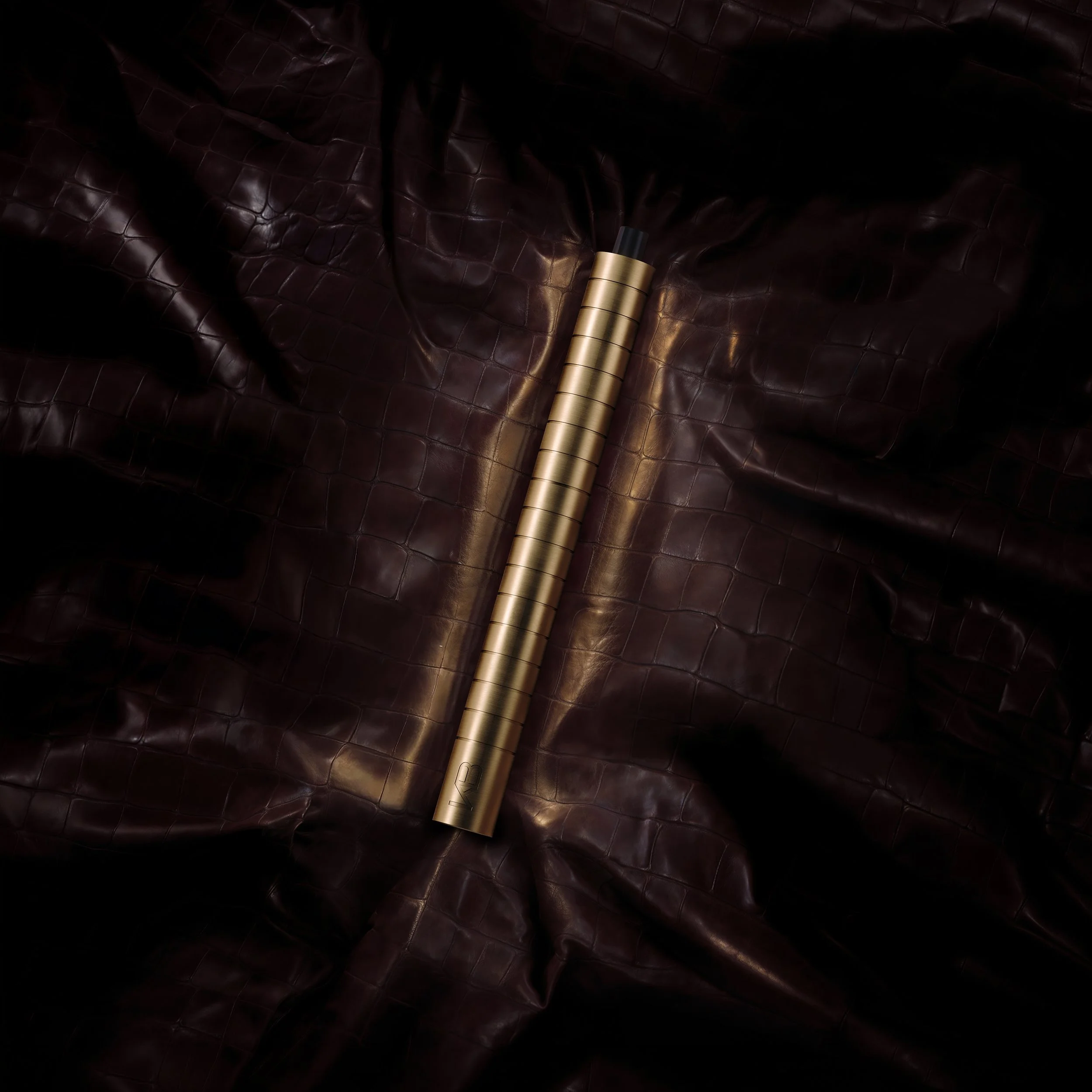 A gold-colored object with black spray nozzle lying on dark brown, textured leather surface.