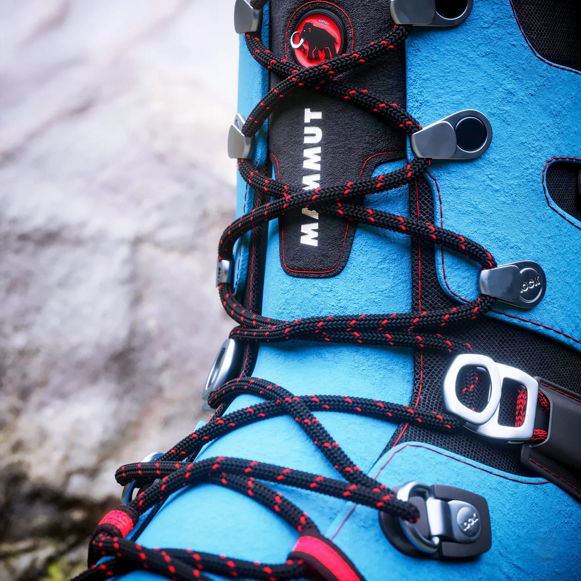 Close-up of a blue hiking shoe with red and black laces, metal hooks, and a Nautik label.