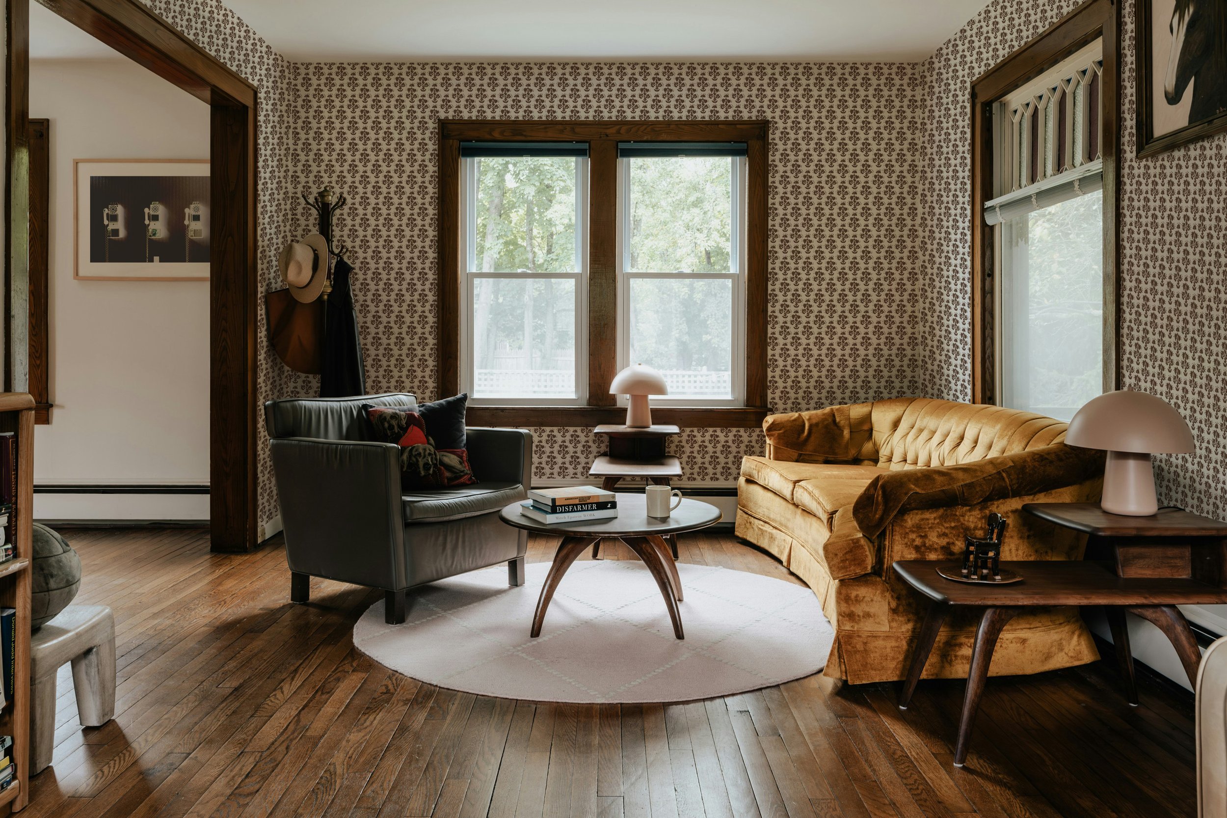 Den with patterned wallpaper, wood built-in bookcases, and a brick fireplace.