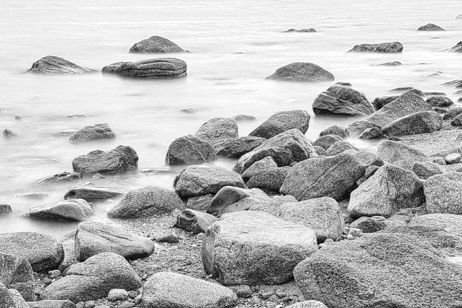Black and white photograph of a rocky shoreline with water over the rocks.