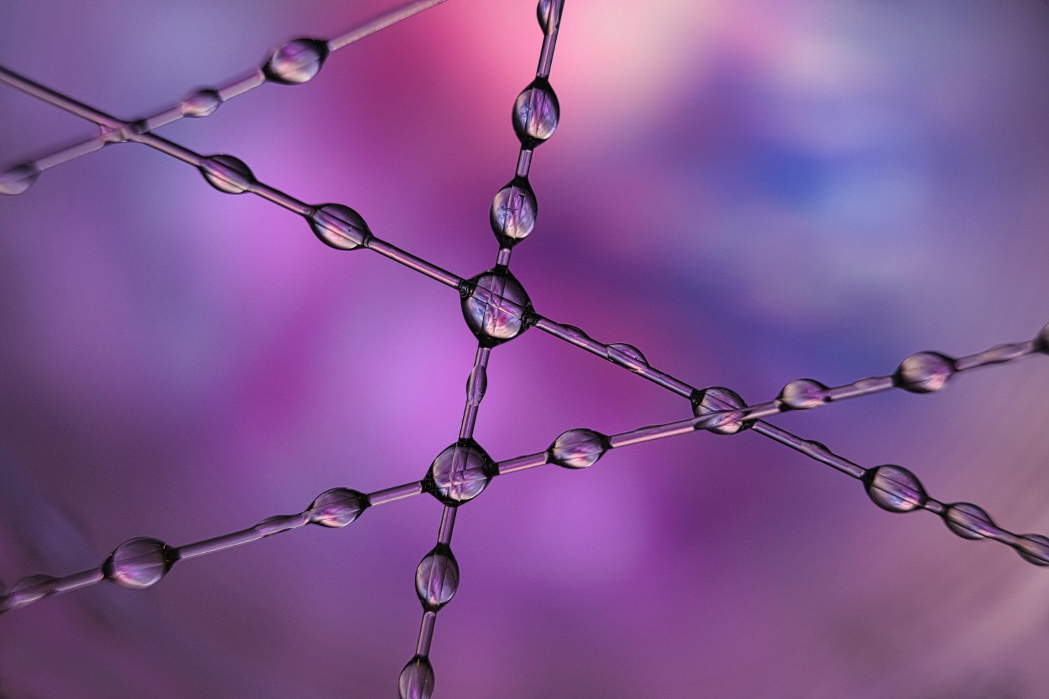 Close-up image of a molecular structure with interconnected spheres and rods, set against a colorful, blurred background with shades of pink, purple, and blue.