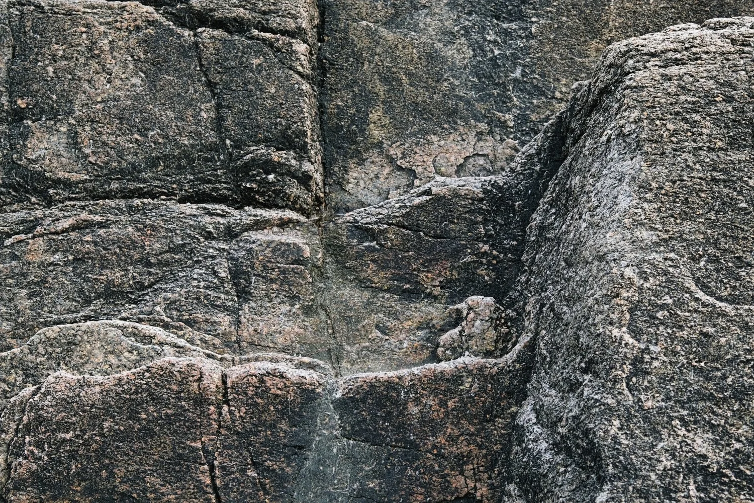 Close-up of dark, textured rocks with various cracks and uneven surfaces.