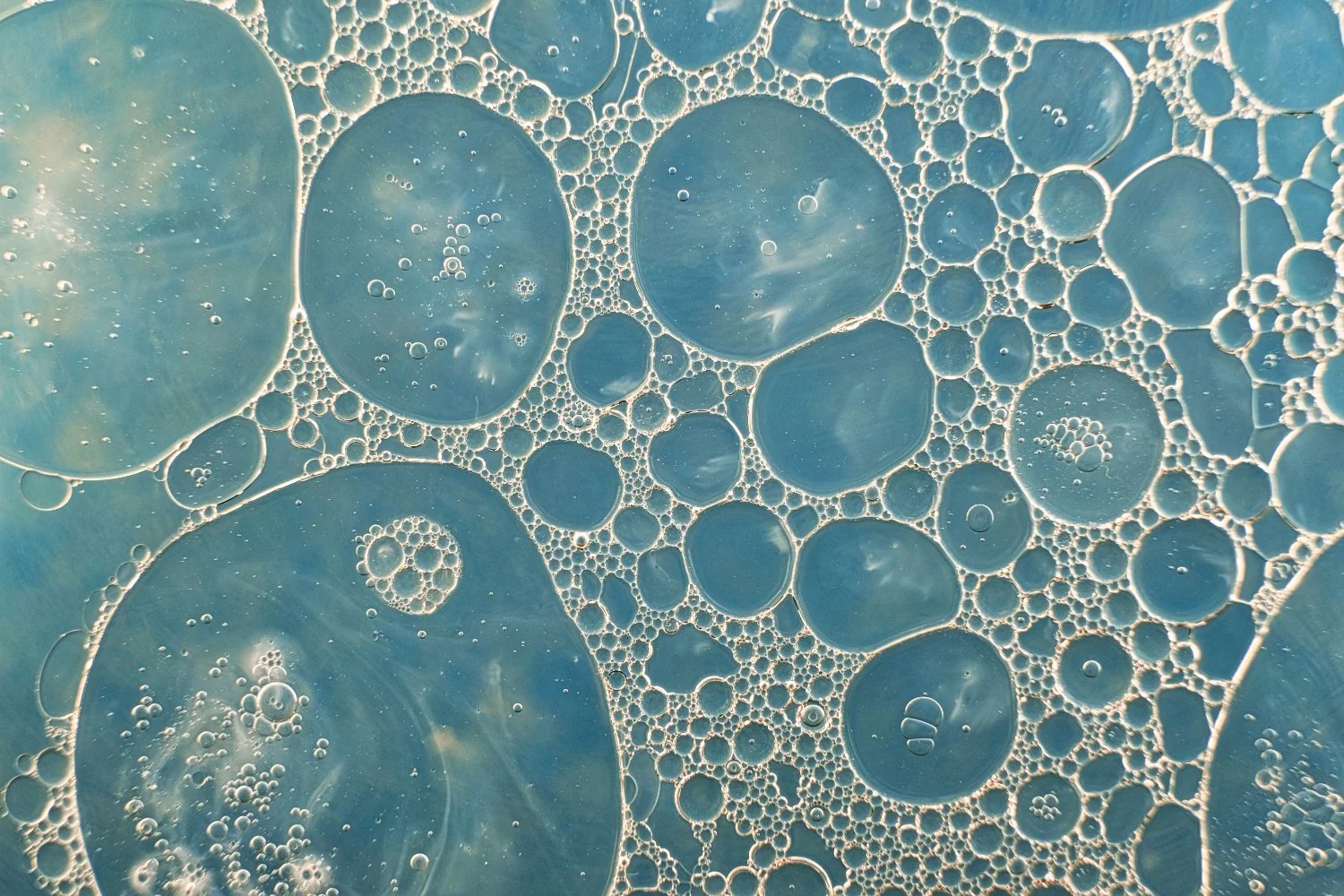 Close-up of bubbles in a blue liquid, varying in size and forming a pattern.