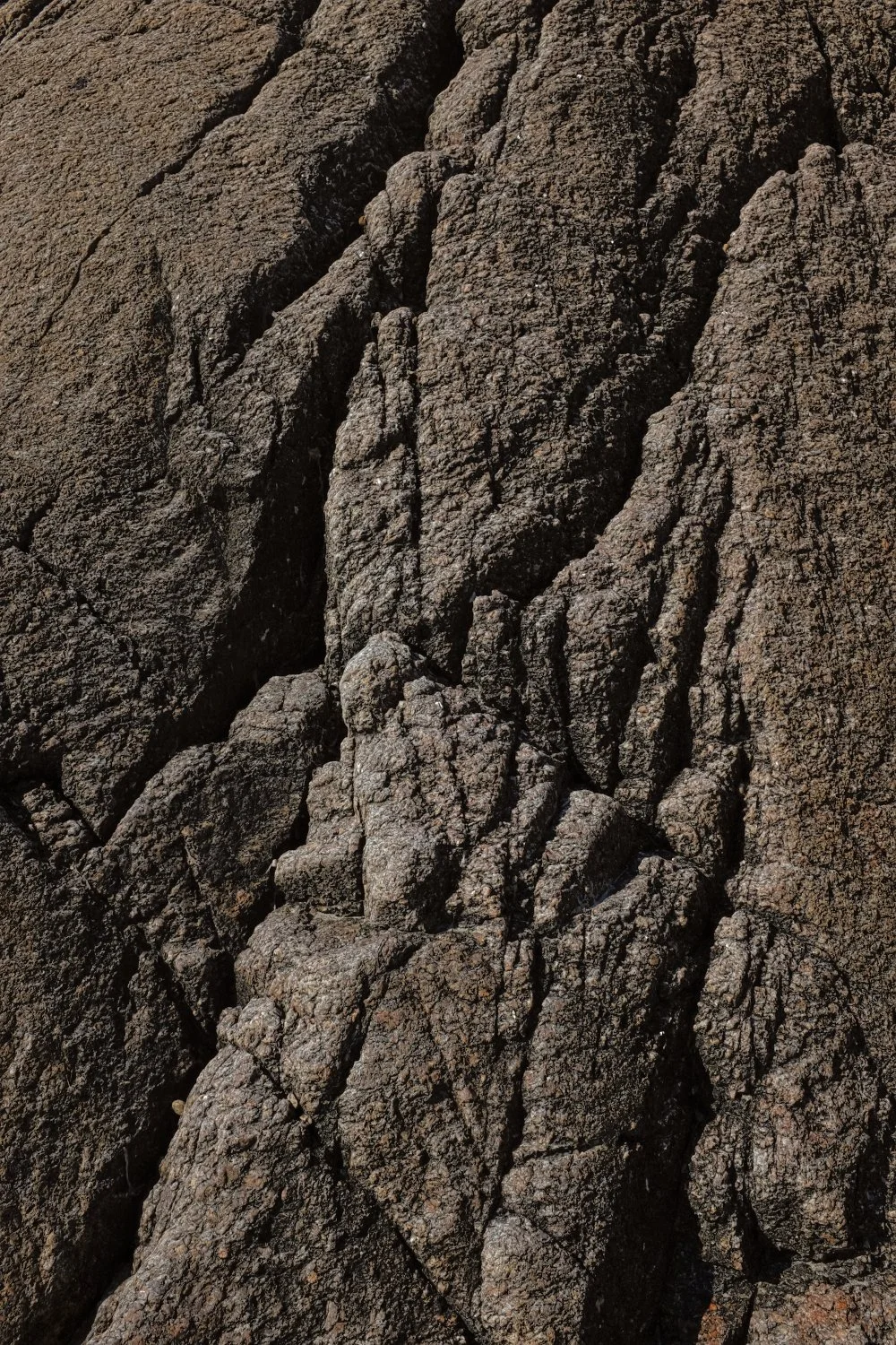 Close-up photo of cracked, black volcanic rock with rough texture.