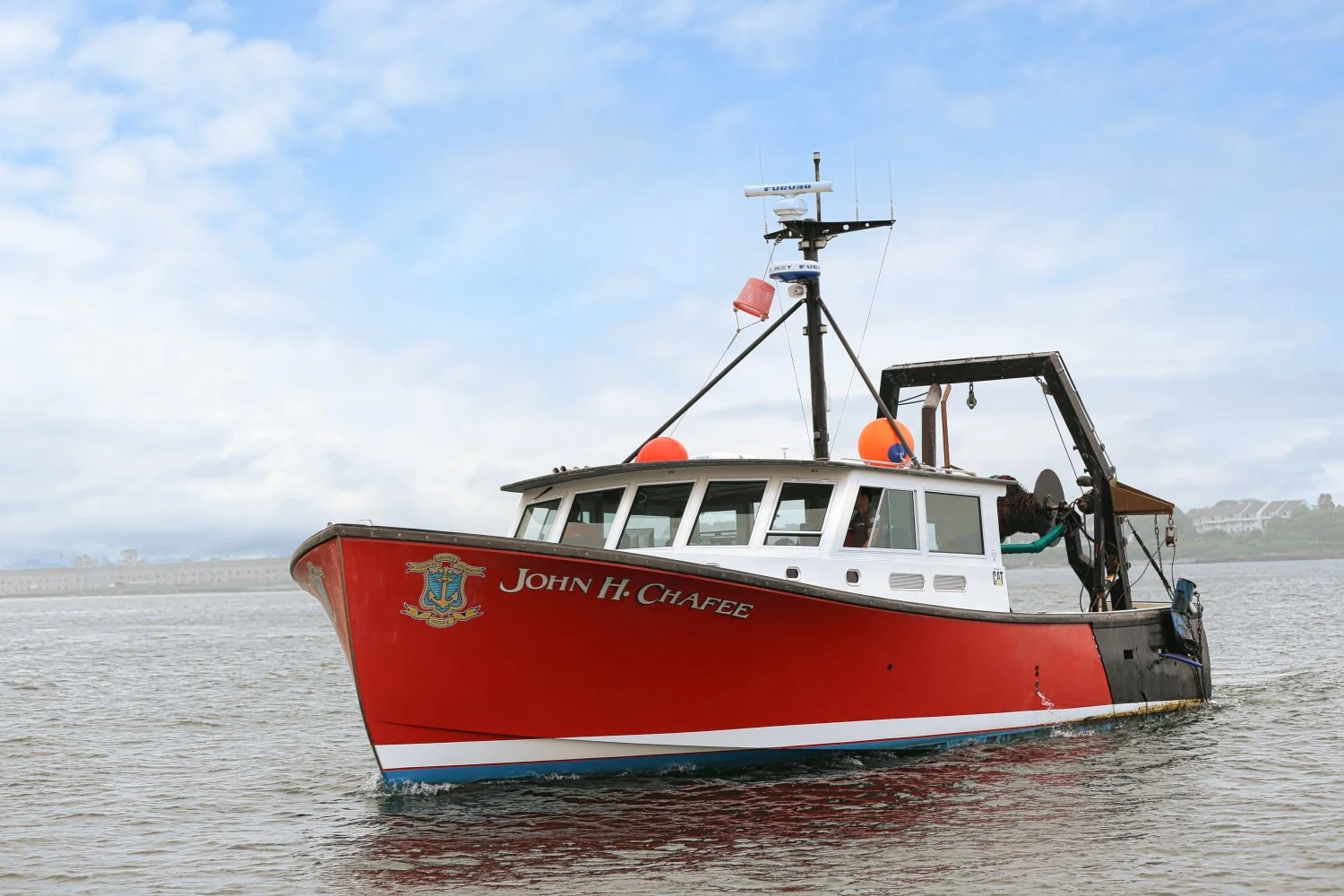 A red rescue boat named John H. Chafee on calm water with cloudy sky in the background.