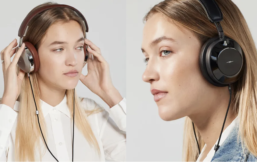 Two women wearing large over-ear headphones, one with brown headphones and the other with black headphones, both with blonde hair and neutral expressions.