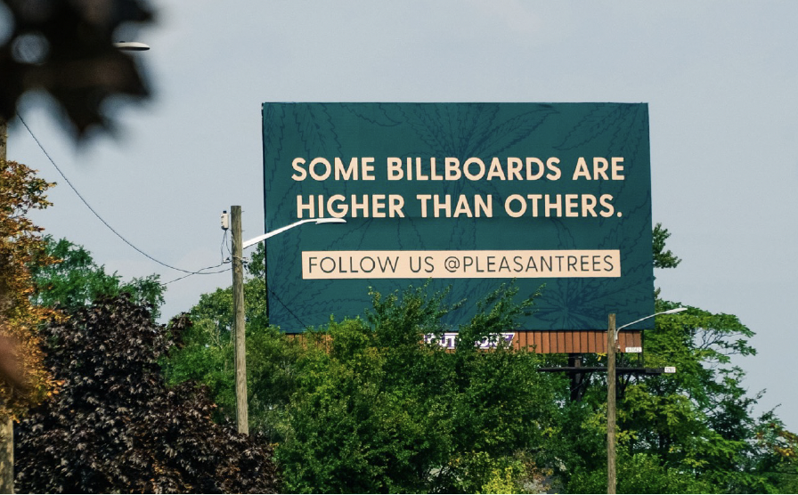 A billboard with a blue background and white text that reads, "Some billboards are higher than others. Follow us @PleasantTrees."