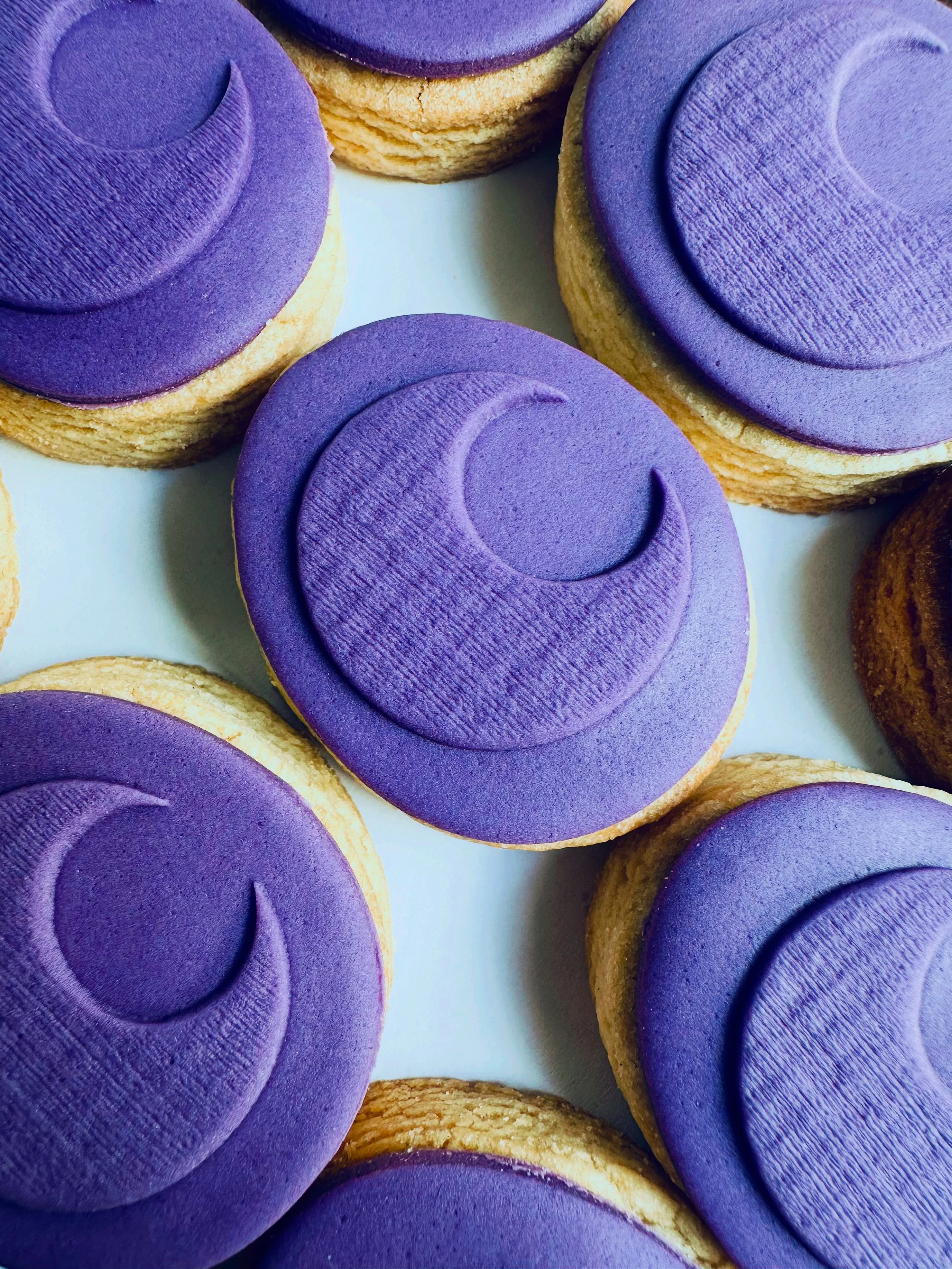 Close-up of cookies with purple icing and swirl design.