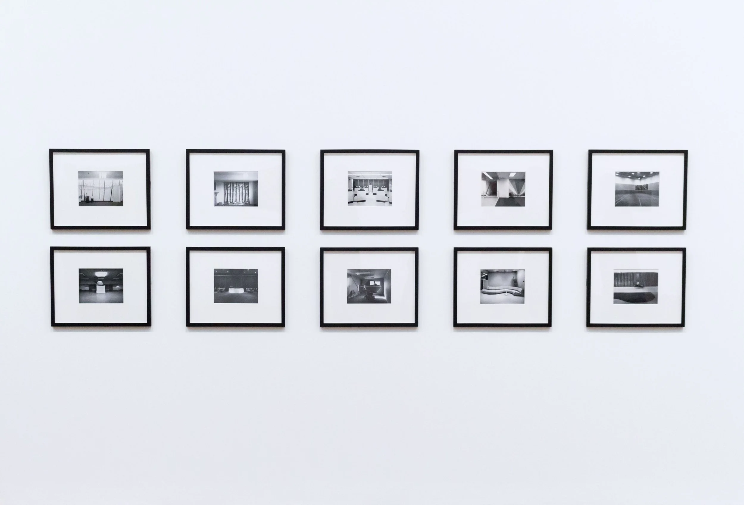 Une galerie d'art avec plusieurs photographies en noir et blanc encadrées suspendues sur un mur blanc.