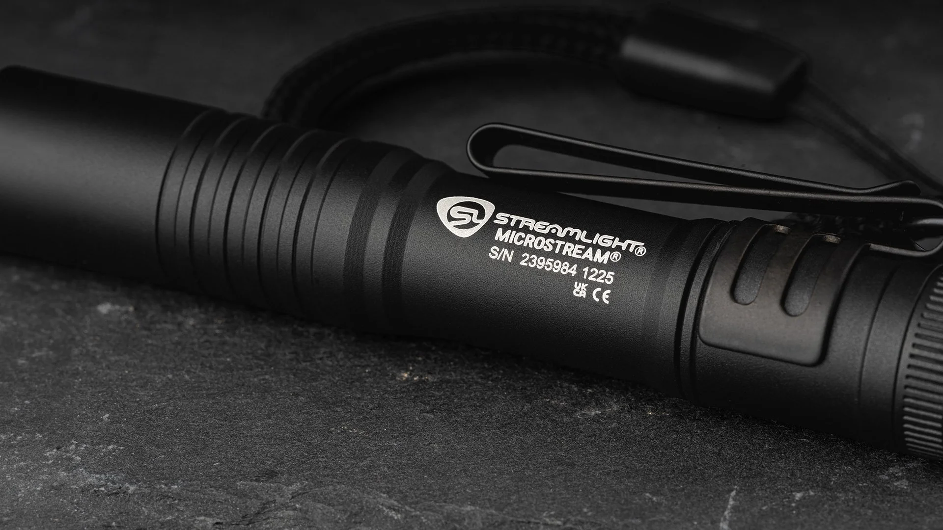 Close-up of a black Streamlight MicroStream flashlight on a dark textured surface.